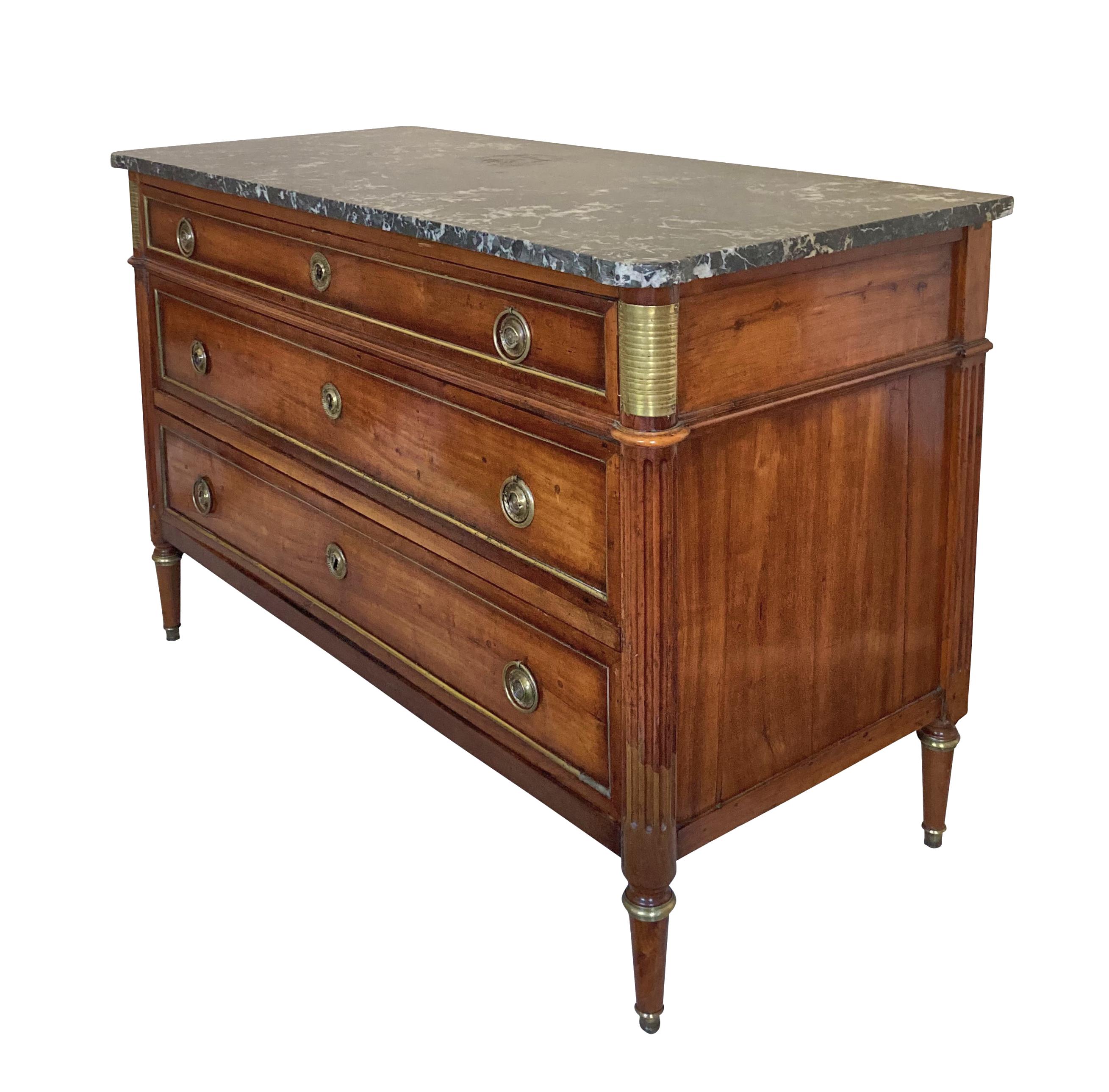 A fine French Louis XVI walnut commode of three drawers, with brass filleting, handles, sabot, and match strikers. The shaped top of variegated grey fossil marble, overall, with very good patina.