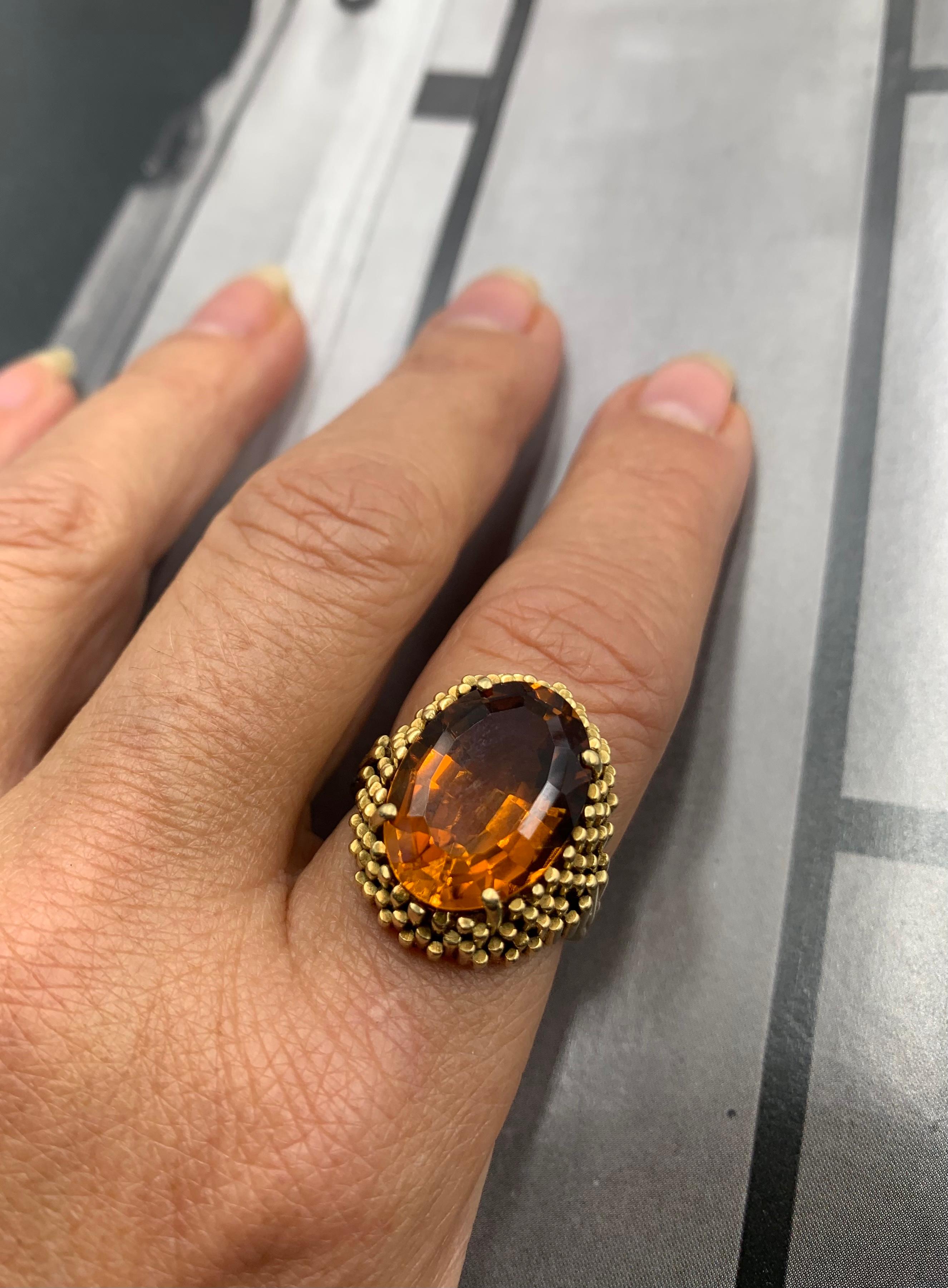 Streamlined, sophisticated Art Deco period 18K gold City Skyline statement ring featuring a superb vivid golden orange oval facet cut citrine of excellent color and clarity. The substantial 18K yellow gold setting is a stylized city skyline composed