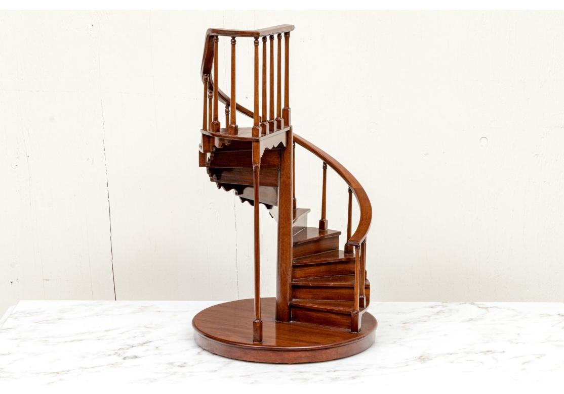 Made in the Philippines A Model Spiral Staircase with a flat curved bannister and shaped steps leading to a shaped landing. With cylindrical supports with turned tops and square bases. Mounted on a circular base. The whole nicely polished.