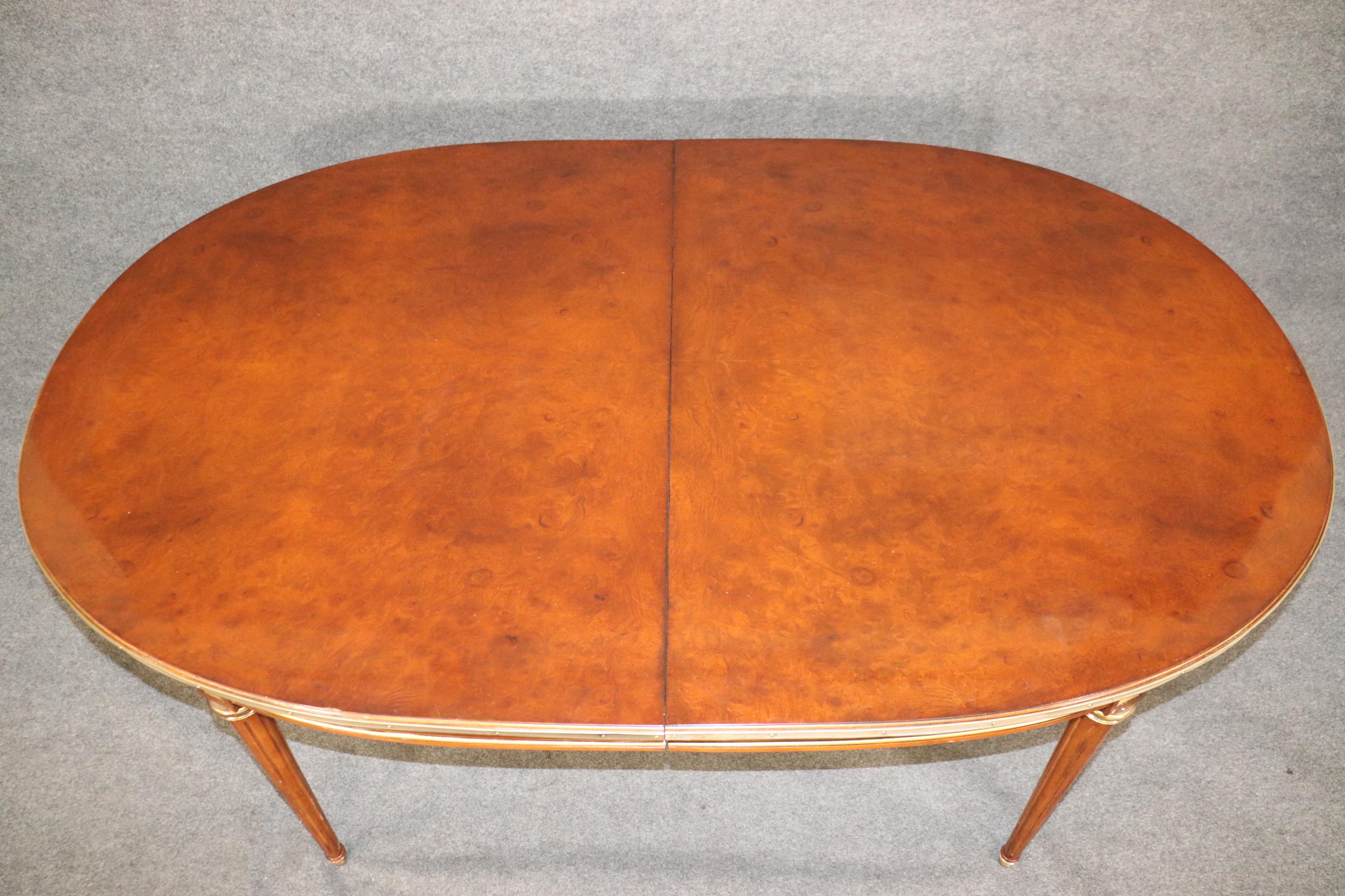 This is a fantasic burled walnut dining table with rich amber coloration and gorgeous brass and bronze trim everywhere on the table frame. The table has a wonderful original finish and no major issues more than minor signs of wear and use but