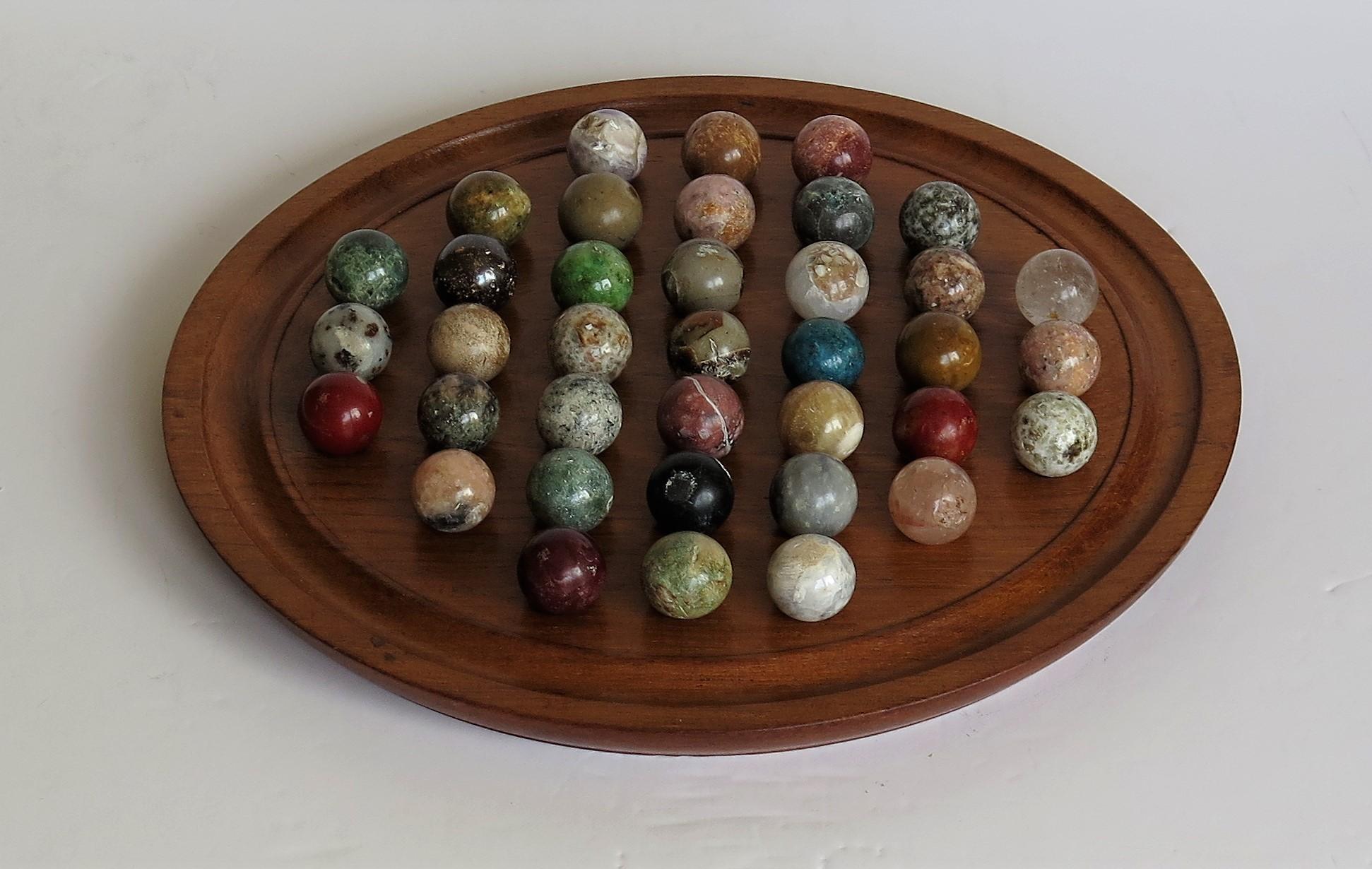 This is a complete board game of 37 hole marble solitaire with a very good 10.5 inch hardwood board and 37 beautiful individual agate mineral stone marbles, which we date to the 20th century, circa 1920 and probably of French origin.

The circular