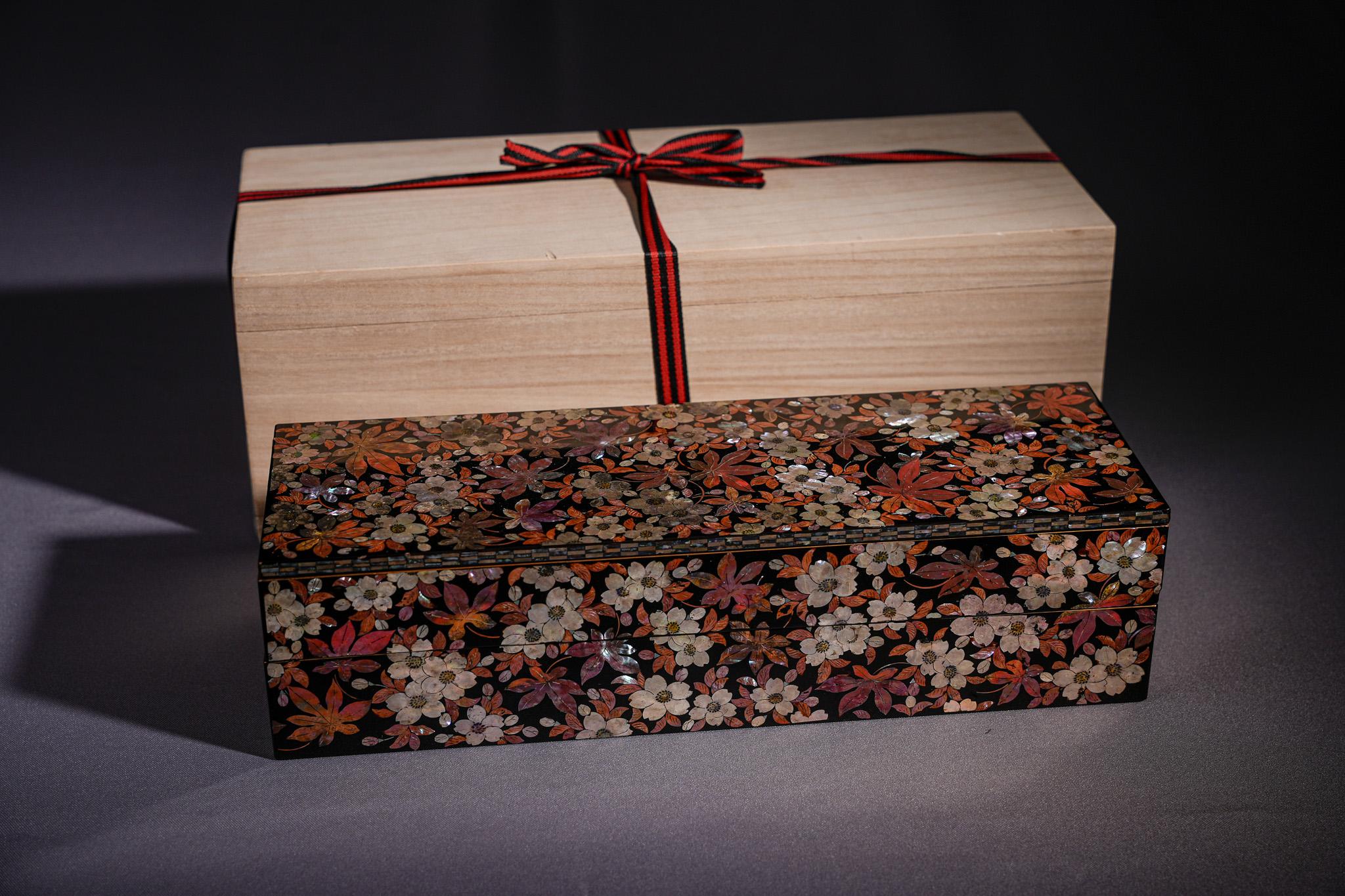 Diese raffinierte rechteckige Lackschatulle wurde in der Meiji-Zeit hergestellt und ist ein Beispiel für die hohe Kunst des japanischen Perlmutts. Der Holzkorpus ist mit tiefschwarzem Lack überzogen und vollständig mit einem üppigen Blütenfeld aus