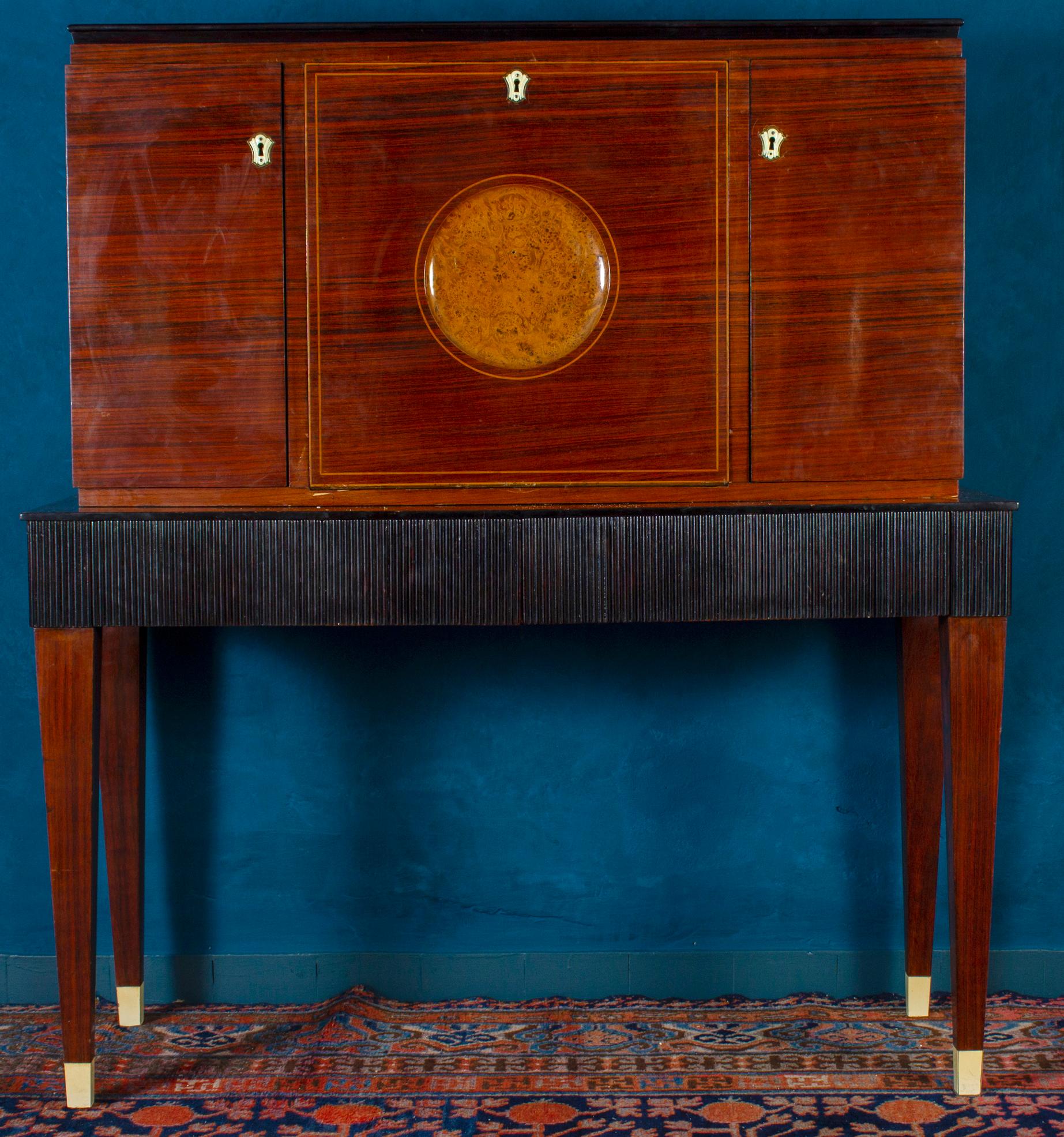 Dry bar, walnut, Italy, 1940s

Elegant Italian bar cabinet in walnut and ebonized wood, inside with Mosaic mirrored glass attributed to Paolo Buffa, 1940.
Lower part with two drawers. 
Furniture for living room or studio of fabulous decor.
In