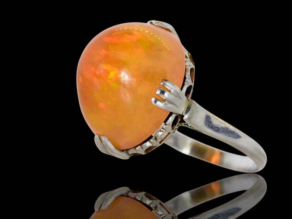 Fine high cabochon fire opal weighing 16.4 cts., set in an antique platinum ring, c. 1915.   This very unusual stone is crystal clear and displays bright yellow, orange, red and green colors.  It has intense vibrant color.  The stone is held in