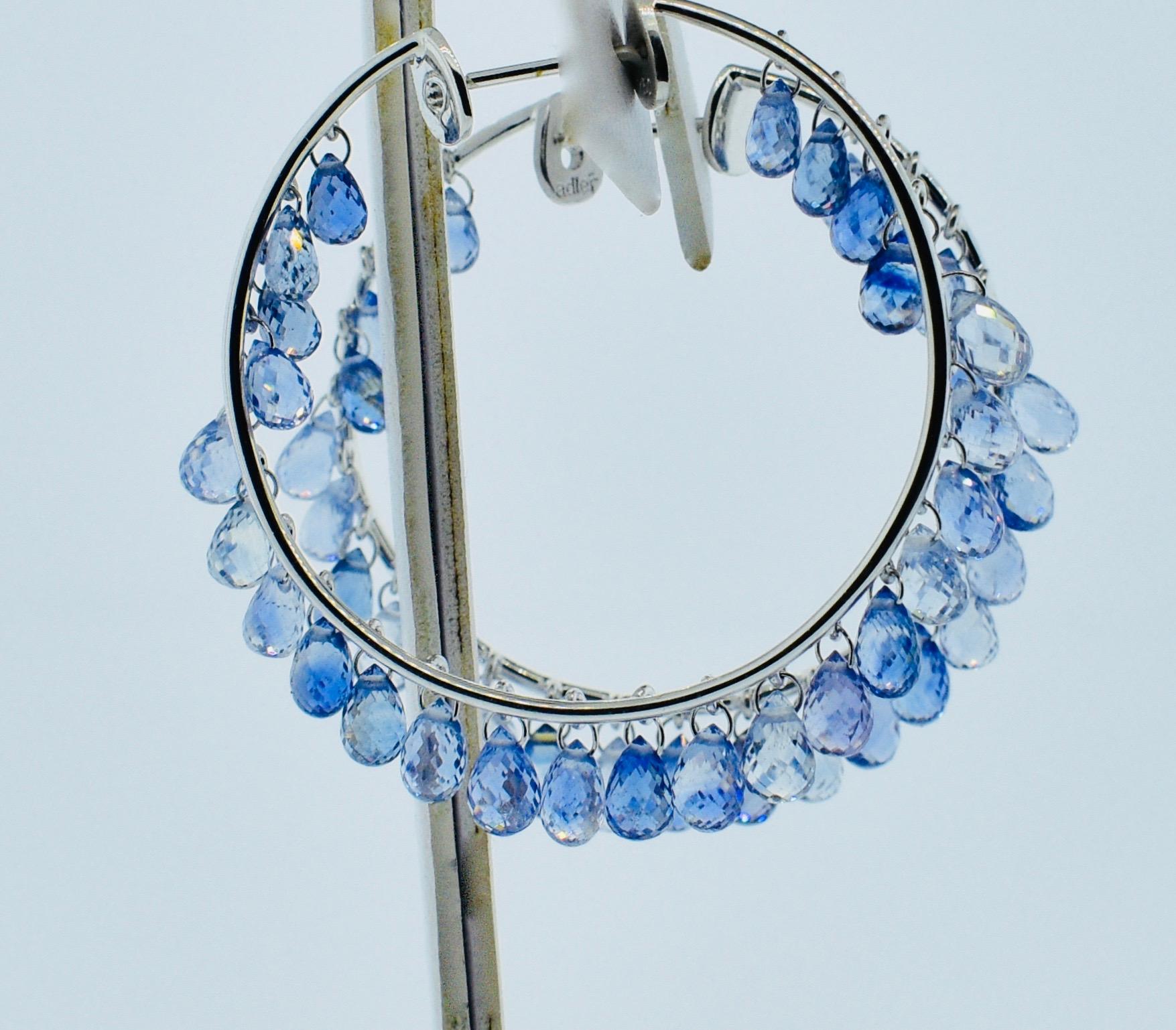Fine natural light blue sapphire and 18K white gold hoop style earrings by Adler - the fine jewelry house in Geneva. These hand made contemporary medium size hoop earrings are an unusual design with fine stones.  50 briolette cut natural sapphires