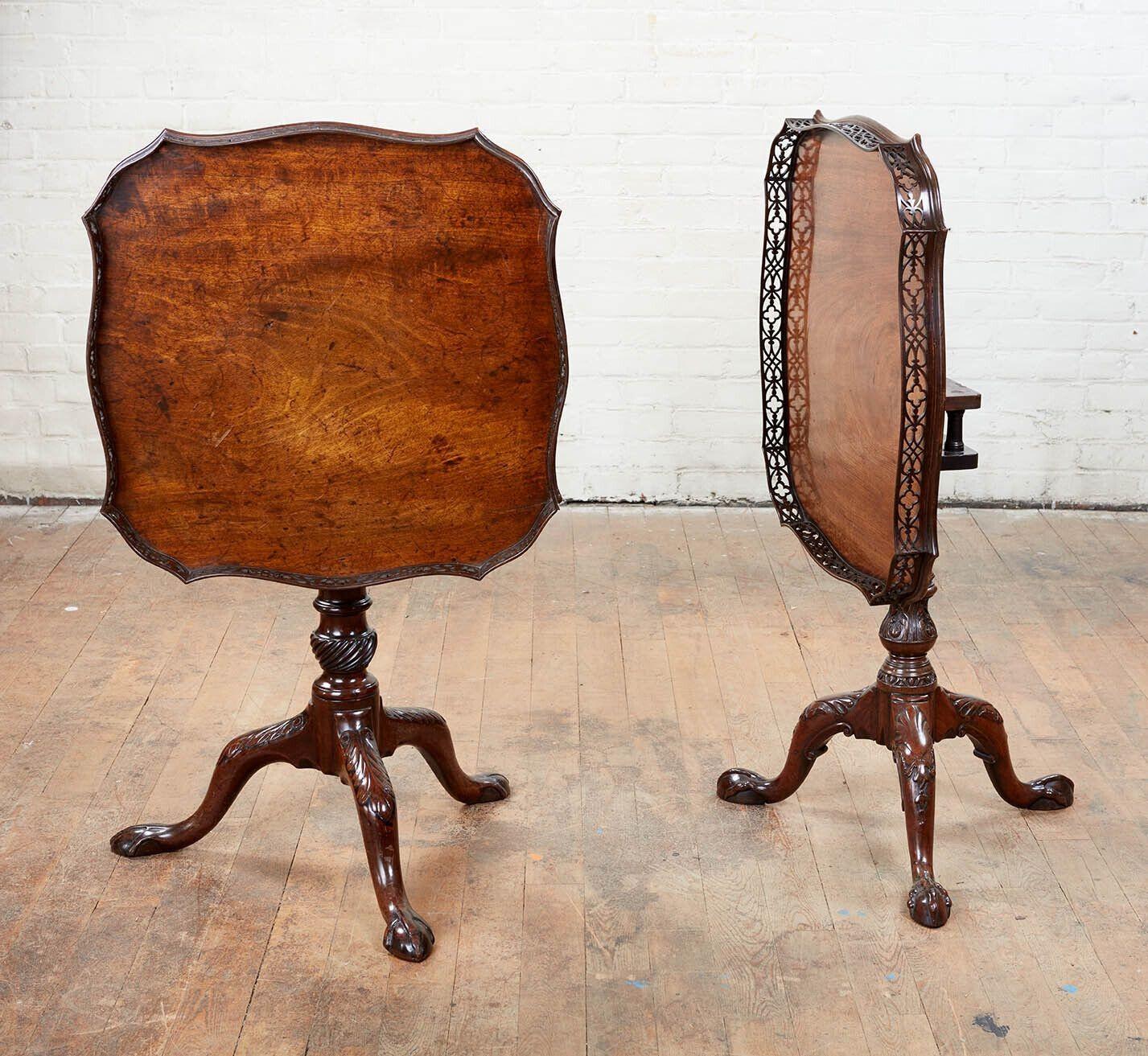 Very fine near pair of George II period padouk fretwork gallery tea tables, the pierced laminated galleries with trellis designs over shaped single board tops, each with birdcage mechanisms and standing on carved tripod bases: one with baluster stem