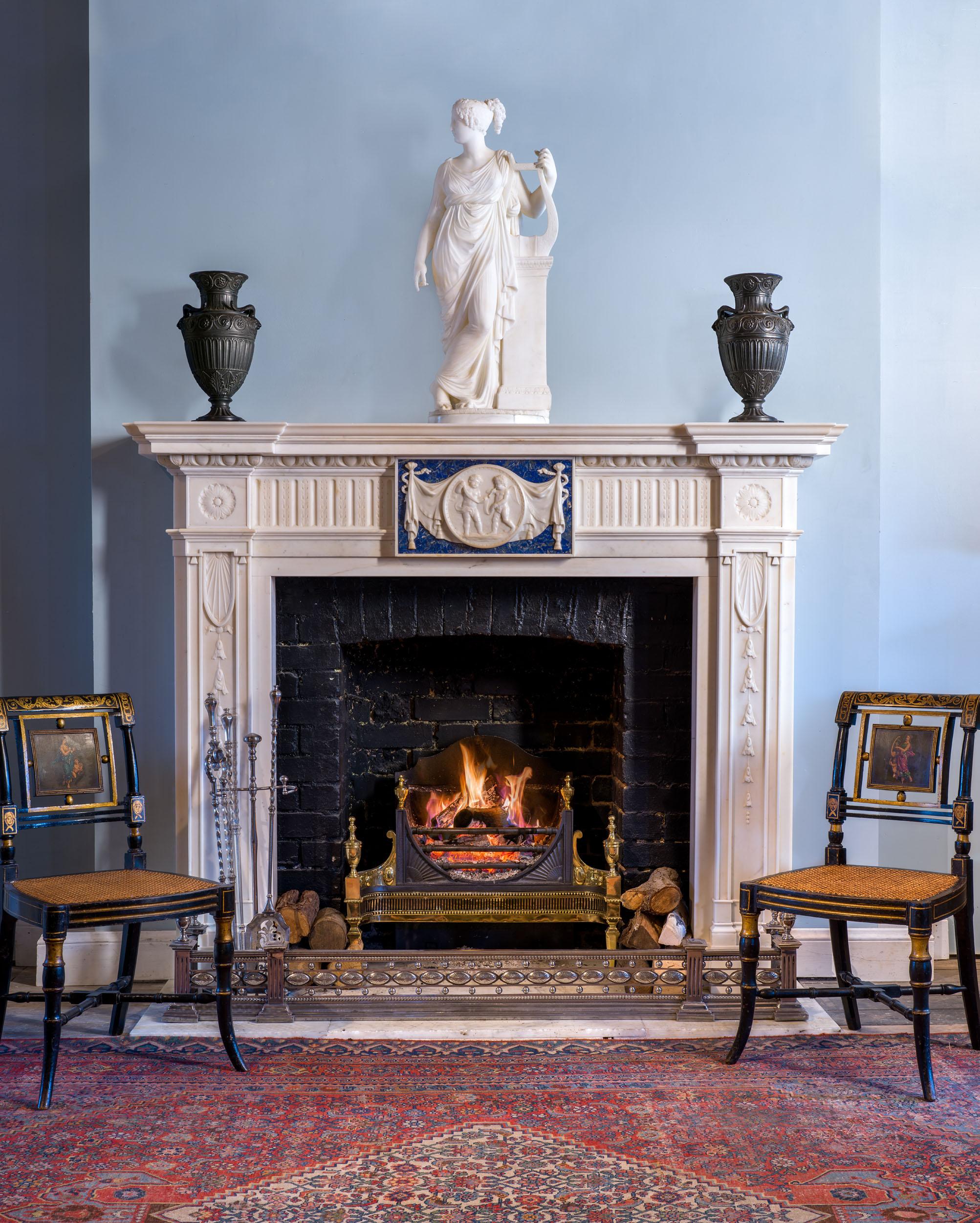 A rare neoclassical chimneypiece of exceptional quality in statuary marble with a lapis lazuli tablet. The inverse breakfront shelf is supported by a boldly carved egg and dart undershelf which rests on a crisply carved, reeded frieze. The frieze is