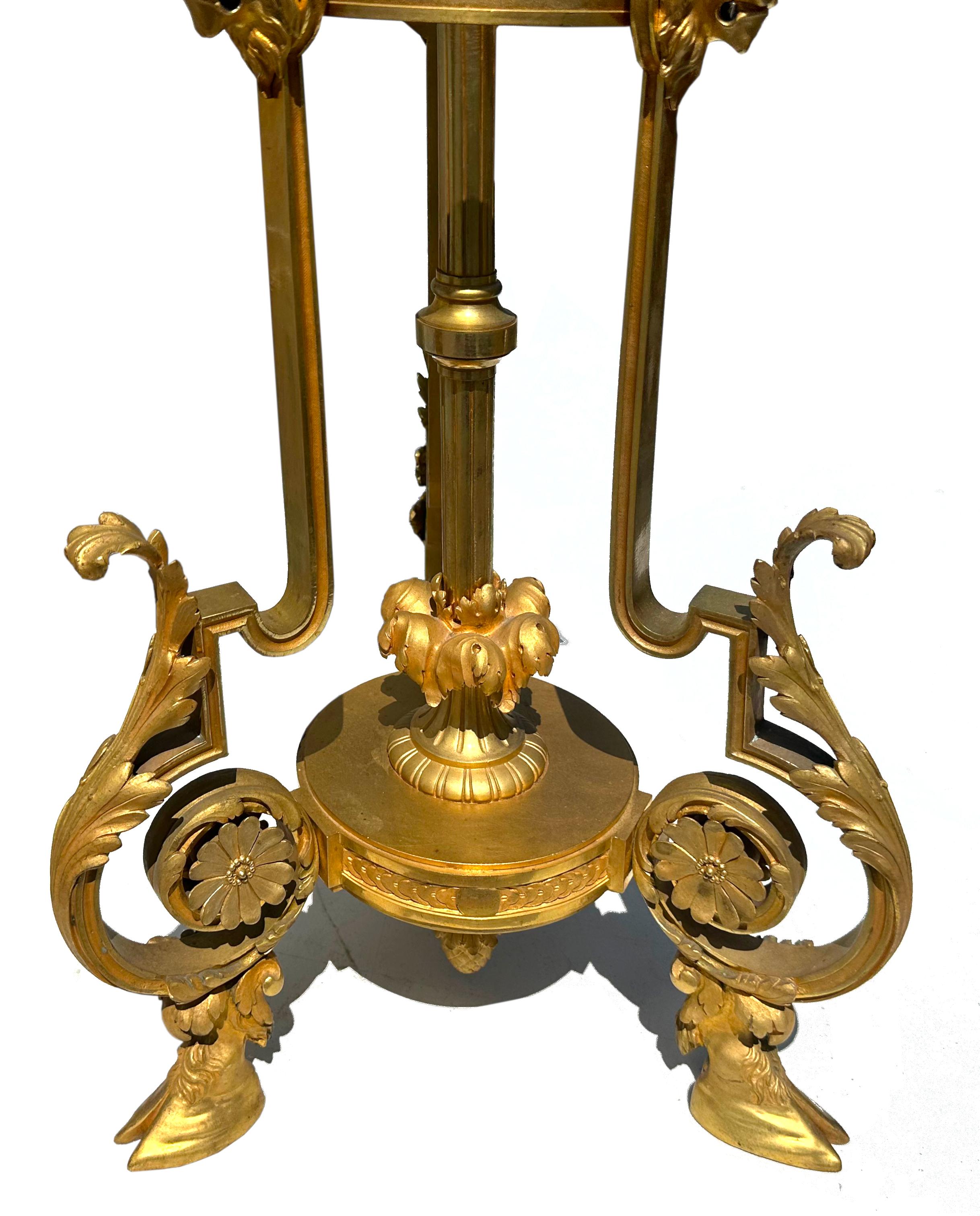 Fina Antorcha de Bronce Dorado de Estilo Neoclásico
Compuesto por tres vértices que se ensanchan hasta los pies acorazados con cabeza de acanto, con un soporte medial en forma de urna con cabezas de carnero, decorado además con guirnaldas y máscaras