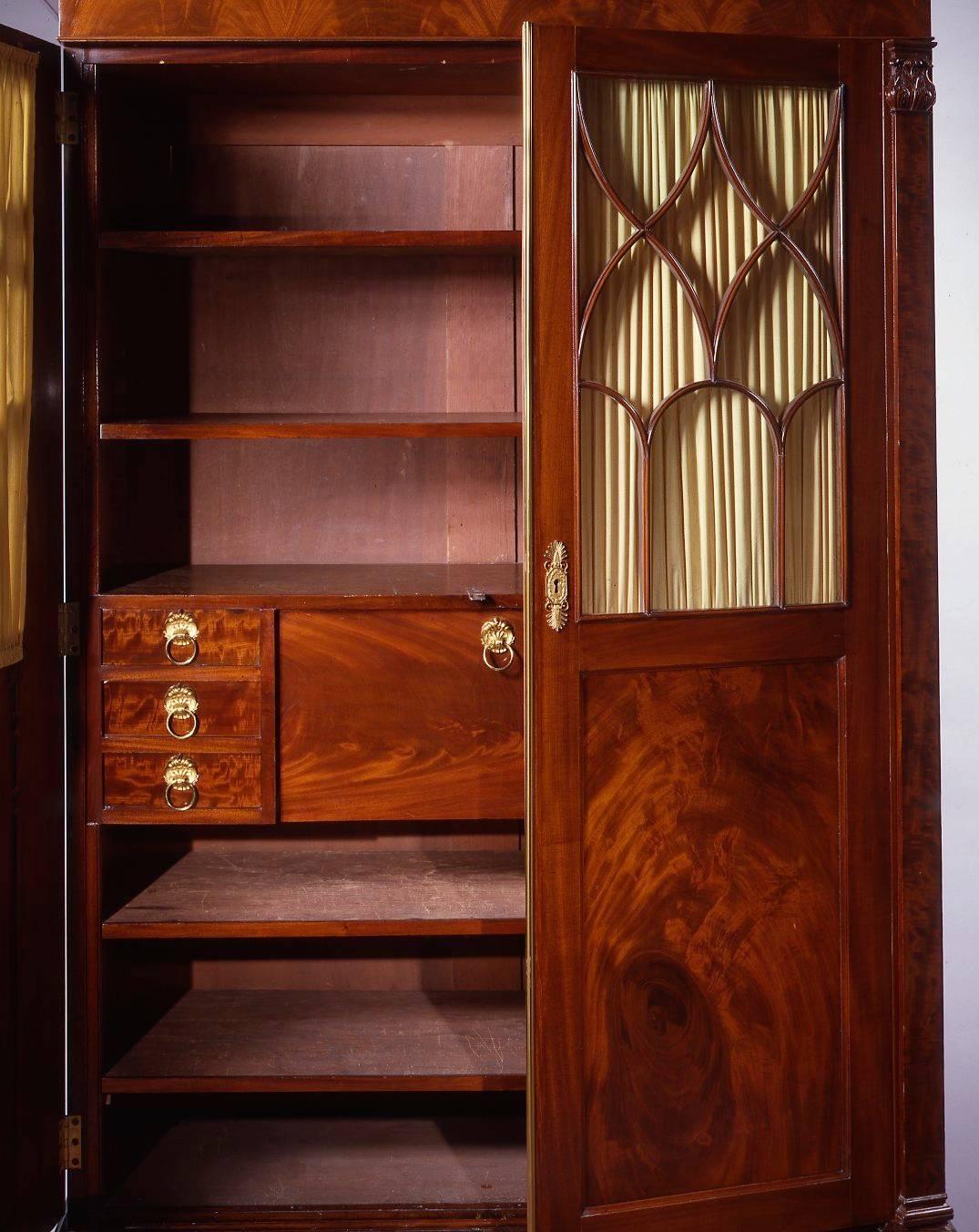 In the Manner of Duncan Phyfe (1770-1854), 
New York, circa 1820

The flat oblong pediment top over a tall case having a pair of paneled cabinet doors with glazed arched and Gothic tracery windows in the top half flanked by pilasters with