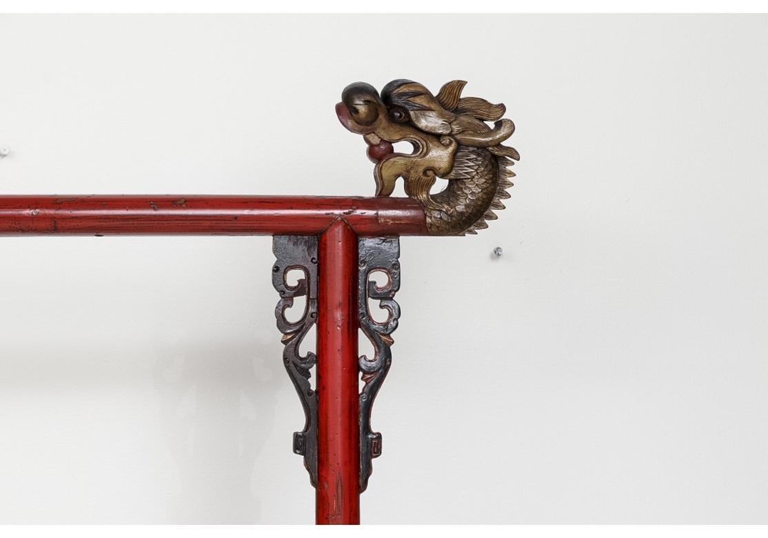 A fine vintage robe rack with generous proportions having a good traditional form. There are two carved dragon head top elements that are powerfully carved, one bearing gilt traces. The color is a striking Cinnabar and the condition is very good