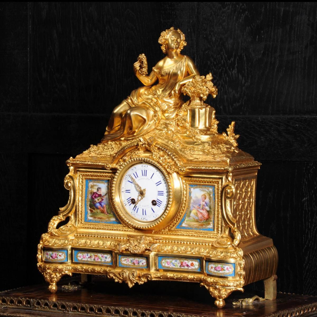 A very fine and early ormolu (finely gilded bronze) clock mounted with exquisite Sèvres style porcelain panels. It features a beautifully modelled figure of a goddess holding a laurel wreath, a symbol of victory. To each side of the dial are