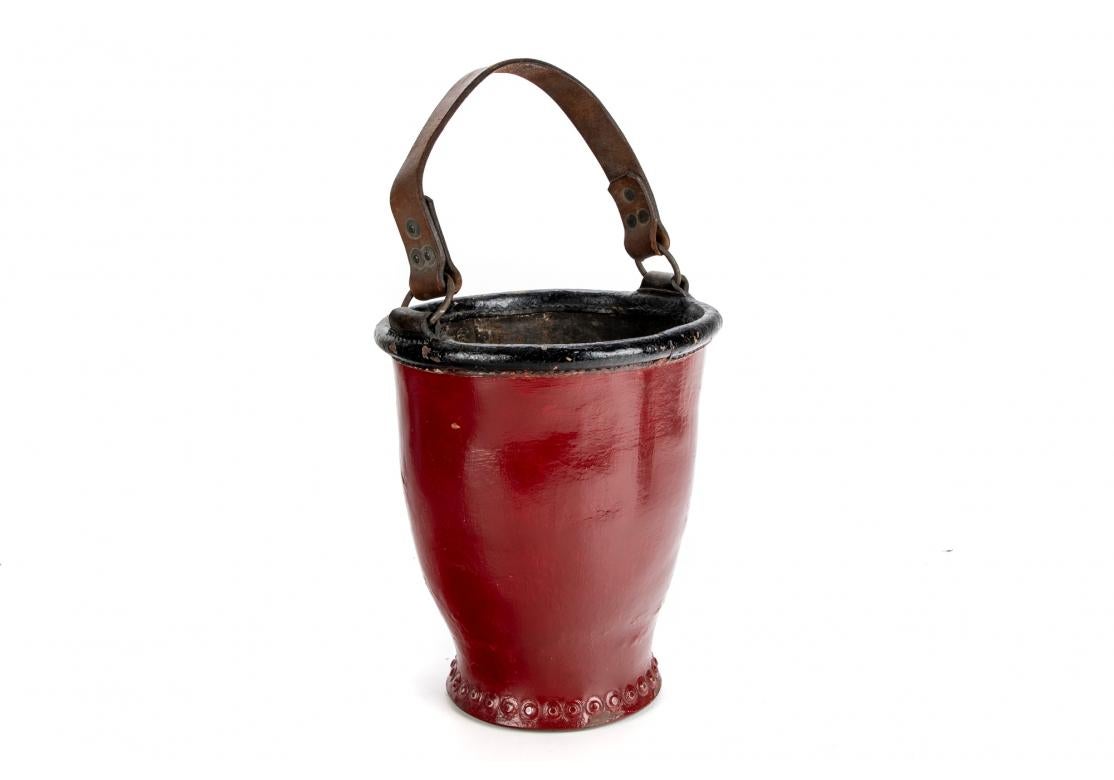 Leather covered wood in red paint with a black top edge and brown leather strap. 
H. 11
