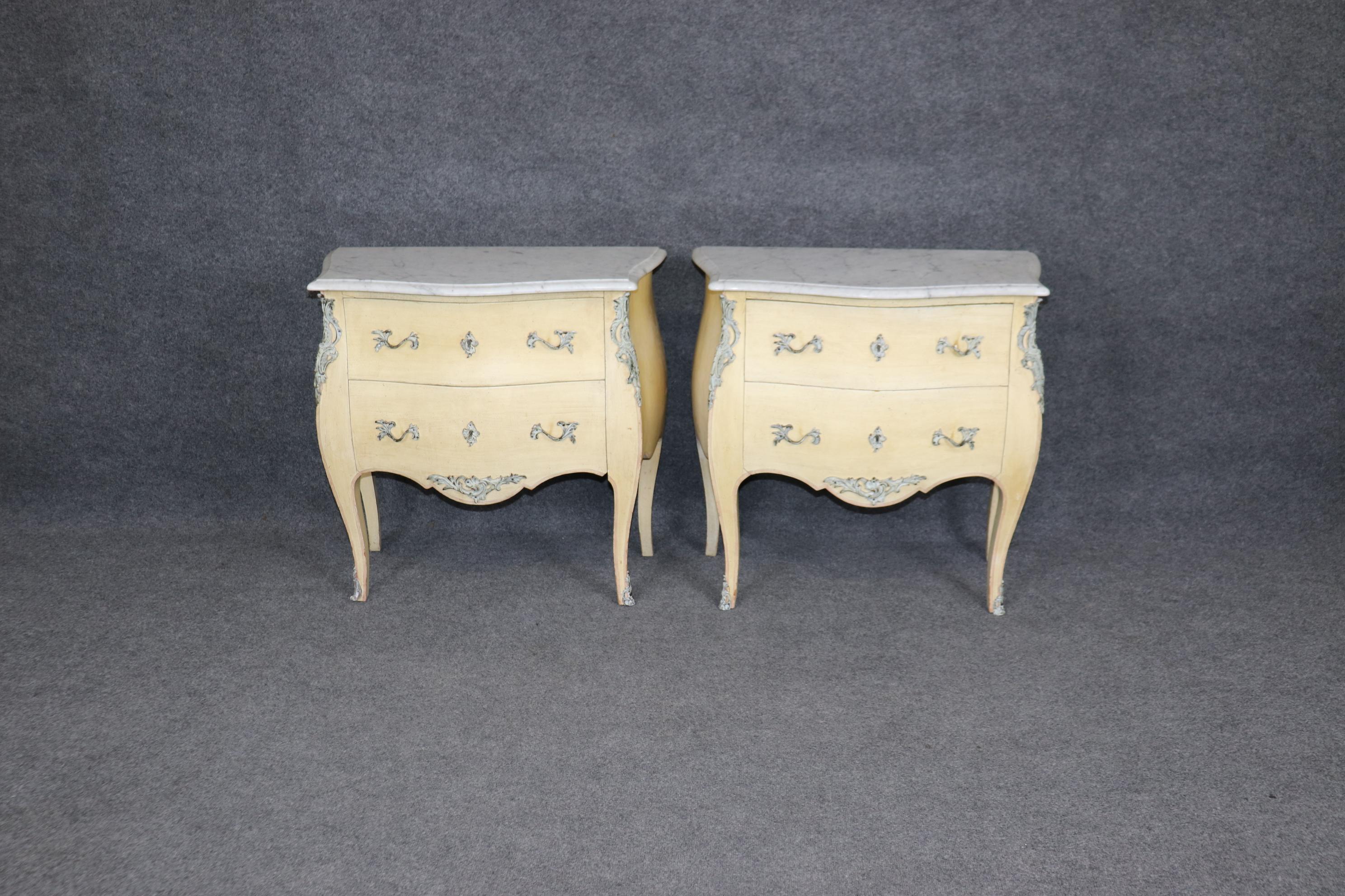 Si tratta di una splendida coppia di antiche commodes francesi in stile bombe Luigi XV. I piani in marmo sono bianchi di Carrara e le casse hanno una finitura bianco sporco antico e sono decorate con vernice color bronzo. Sono in buone condizioni,
