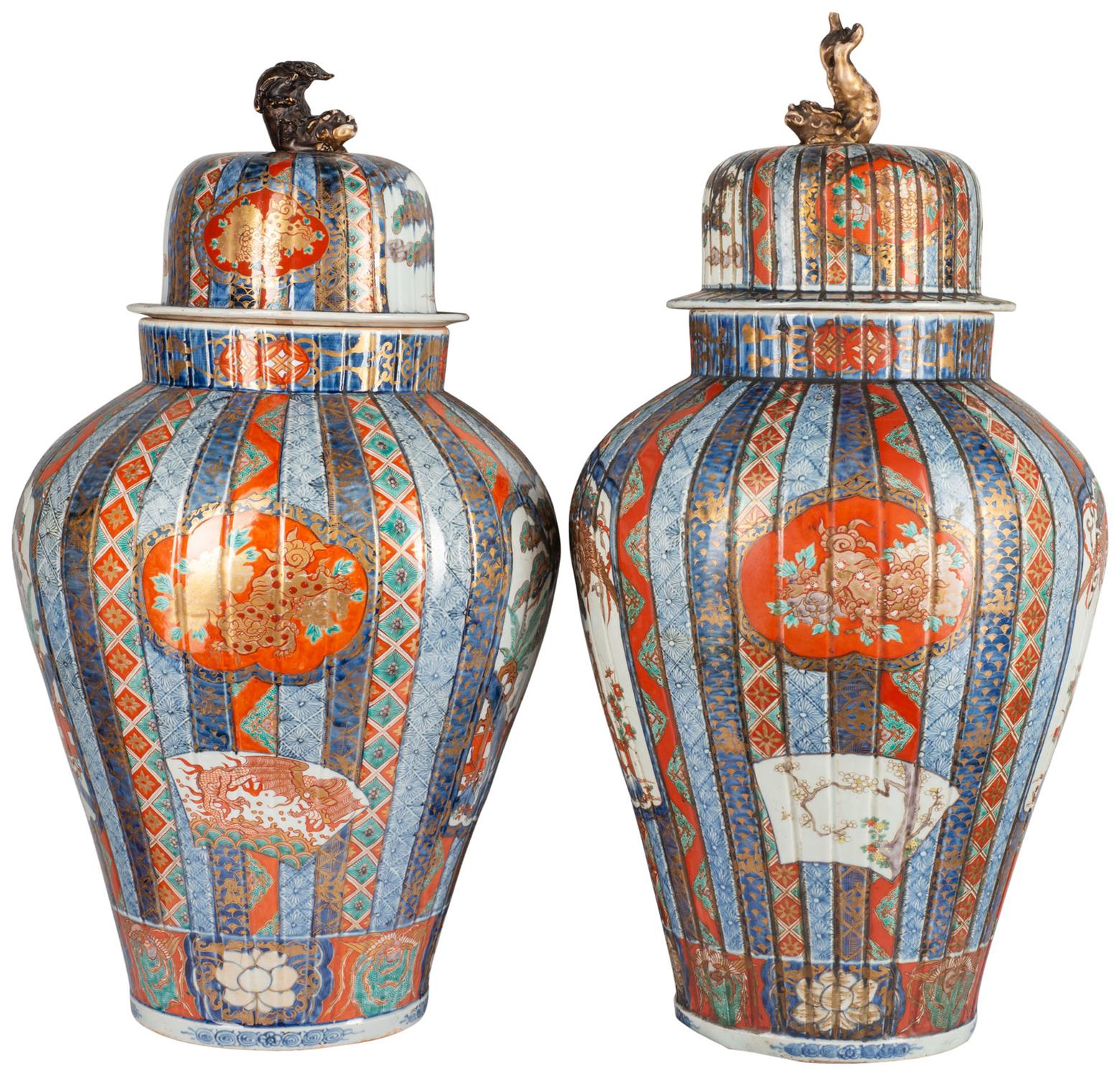 A very good quality pair of 19th century Japanese lidded Imari vases, each with mythical creatures as finials, the lids and vases with reeded detail, classical motif and floral decoration within. Inset painted panels depicting blossom trees, exotic