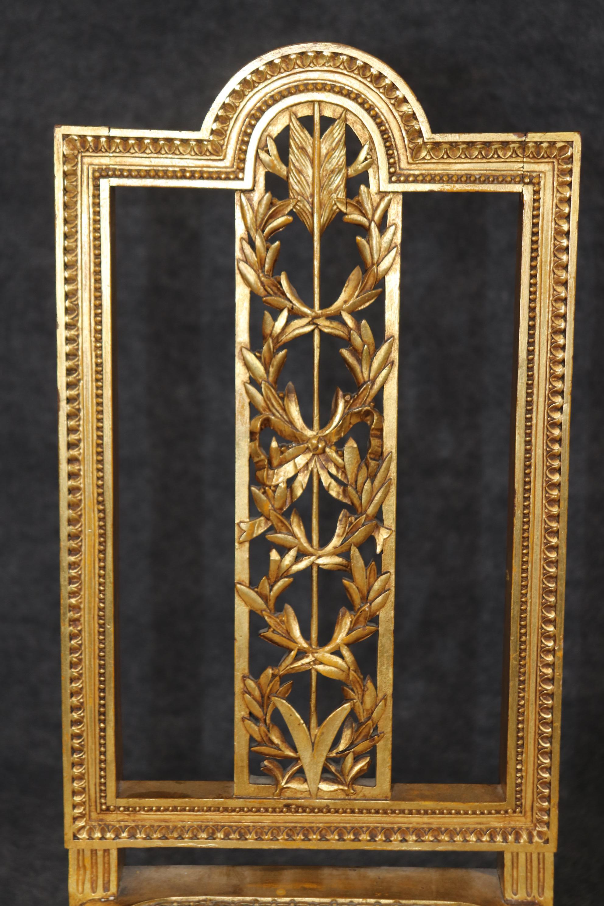These are absolutely luminous and bright genuine gold leaf gilt carved arrow and floral motif side chairs. They are perfect for use in a foyer as entry way chairs or for a bedroom. The seats are in good condition with minor but stable cane breakage