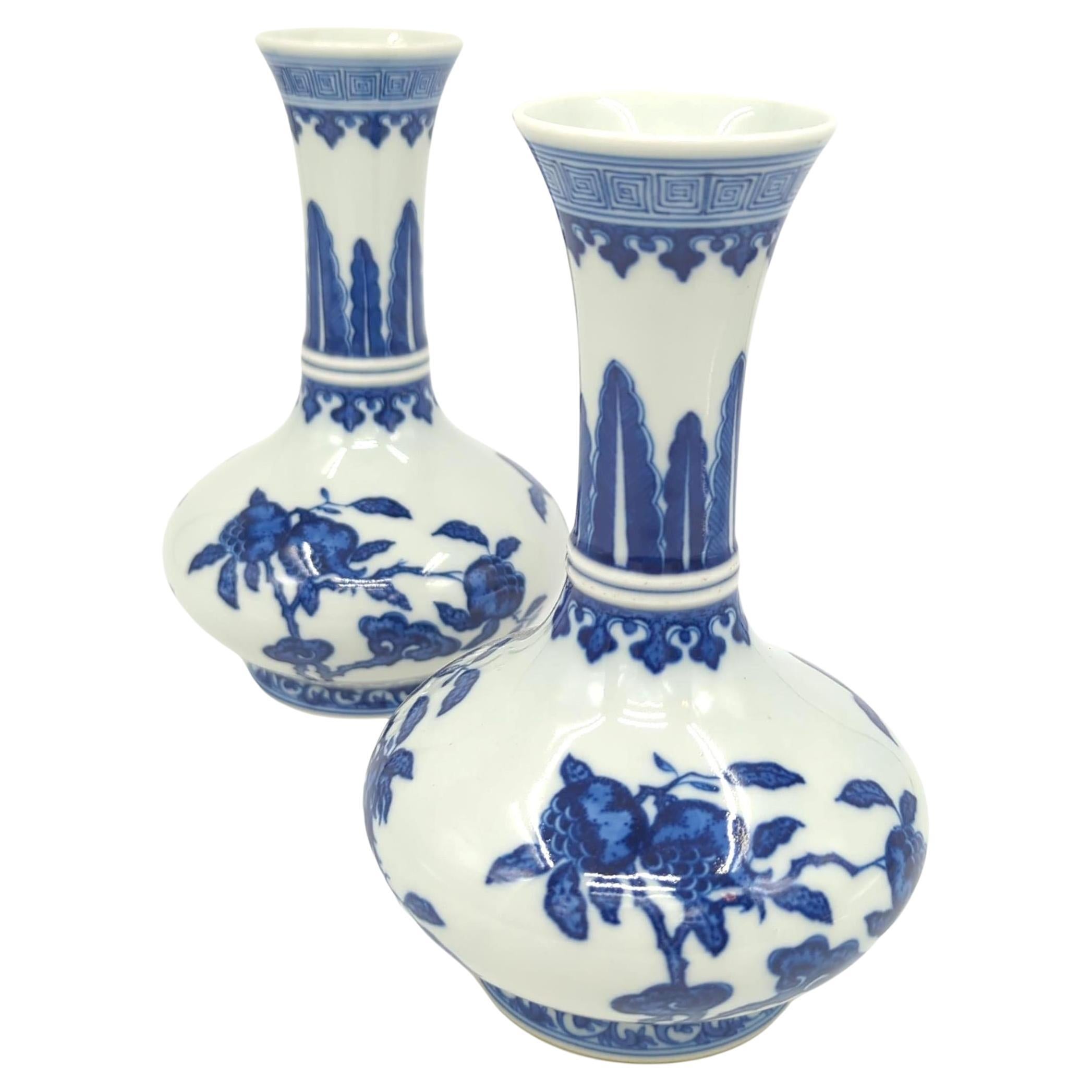 We are pleased to offer this pair of late 20th-century Chinese porcelain vases, exemplifying the enduring legacy of Chinese ceramic artistry. Each vase is of a compressed globular form, featuring a ribbed neck that culminates in a trumpeting mouth,