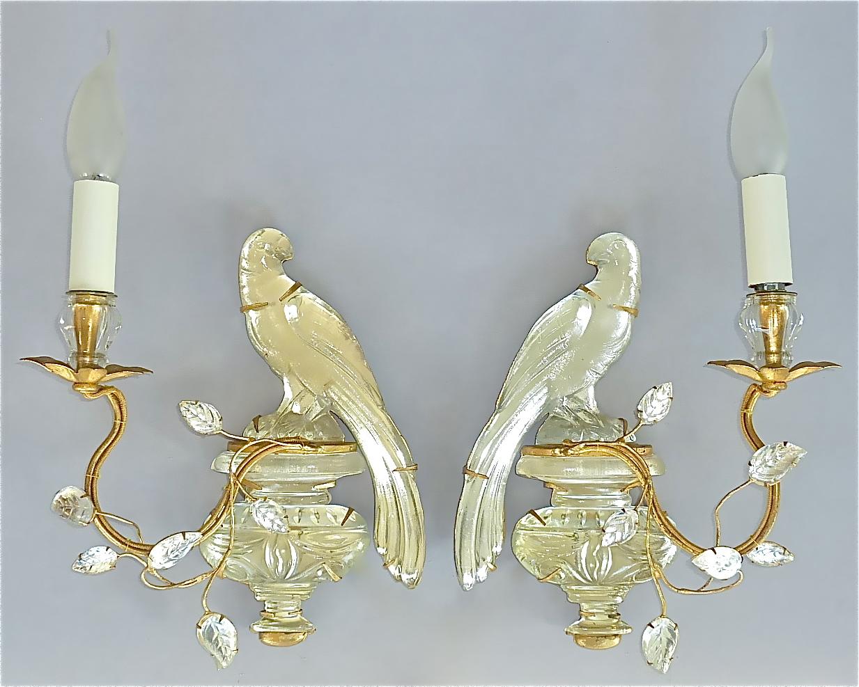 Fine and elegant pair of French handcrafted gilt brass metal and faceted crystal glass parakeet sconces by Maison Bagues, France circa 1950s to 1960s. Each Midcentury wall light displays a beautiful crystal urn with a charming and wonderfully