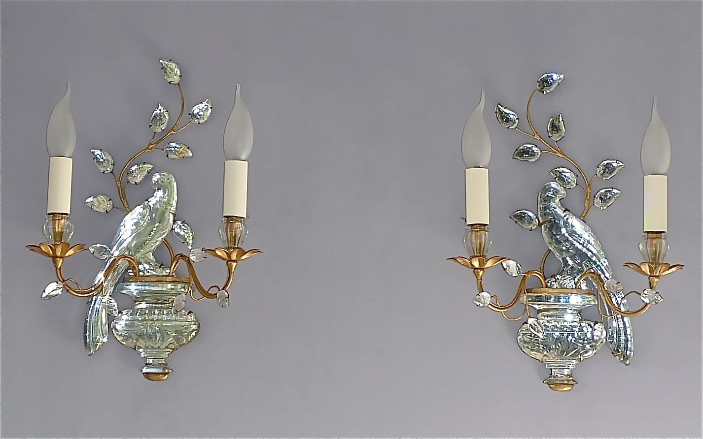 Fine and elegant pair of French hand-crafted gilt brass metal and faceted crystal glass parakeet sconces by Maison Bagues, France circa 1950s to 1960s. Each Midcentury wall light displays a beautiful crystal urn with a charming and wonderfully