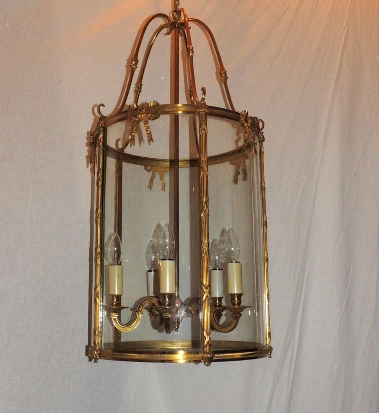 Un'elegante lanterna a cinque luci in bronzo dorato con finiture in bronzo a coste incise sulla parte superiore e inferiore della lanterna, con finiture in canna scanalata con fiocchi incrociati intorno a un pannello di vetro curvo accentato con