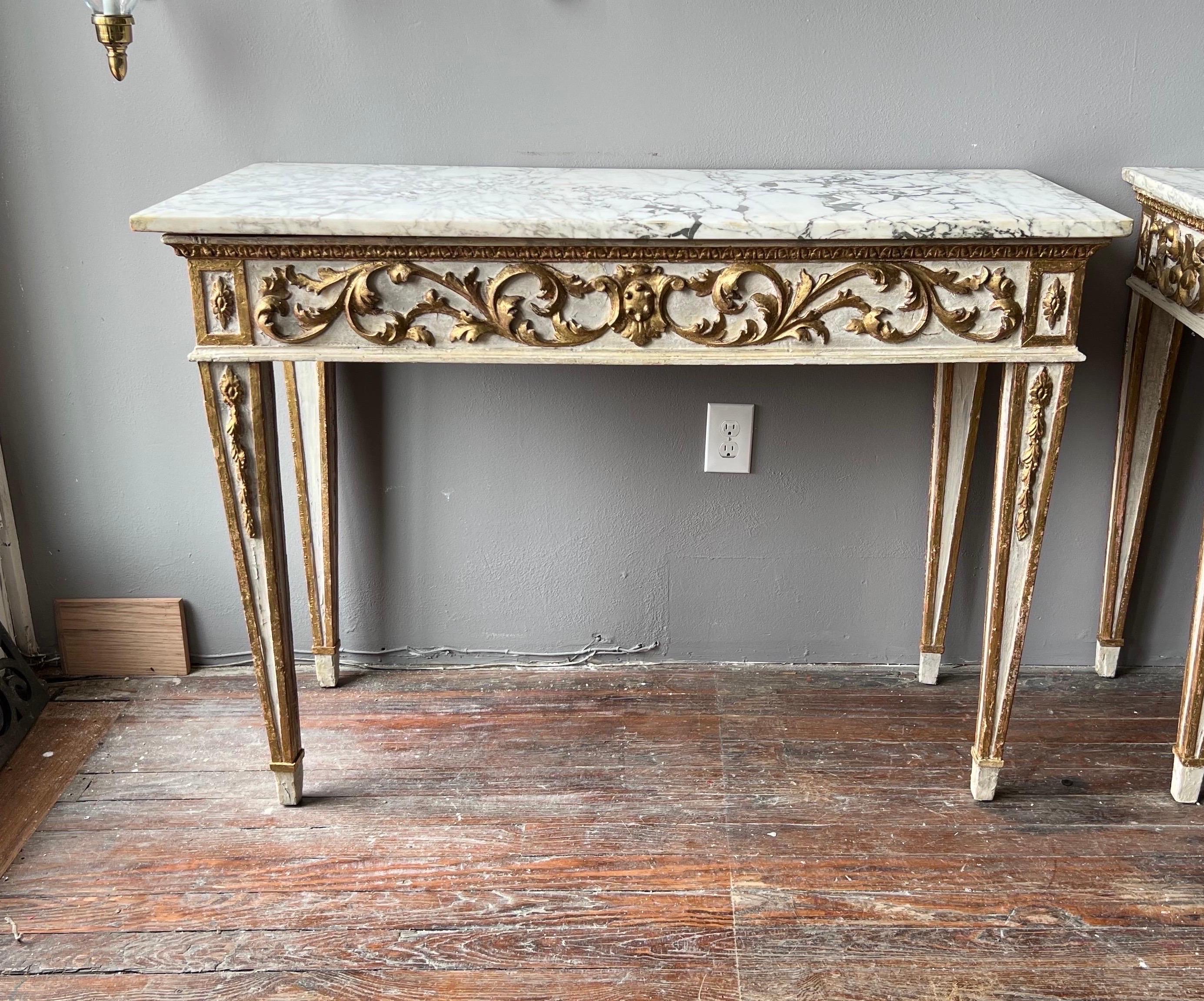 Very fine pair of 18th century French neoclassical gilt wood and paint decorated marble top consoles on tapered legs with bellflower and original chiseled marble.