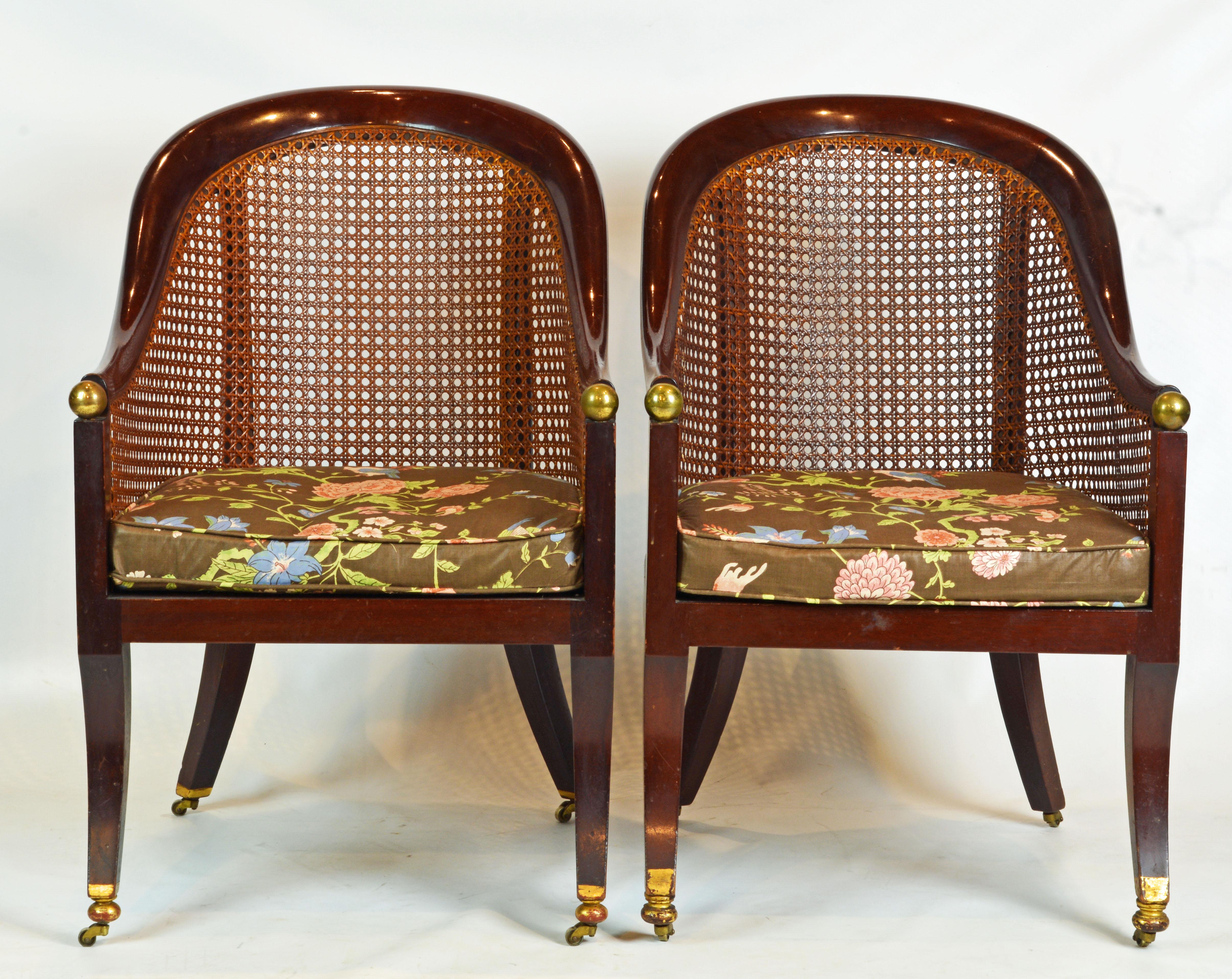 These chairs feature arm rests and back rails designed as continuous elegant curves joining the sabre style front legs by a brass ball. Back, sides and seat are mounted with woven cane and the rear legs continue in uprights to support the back rail