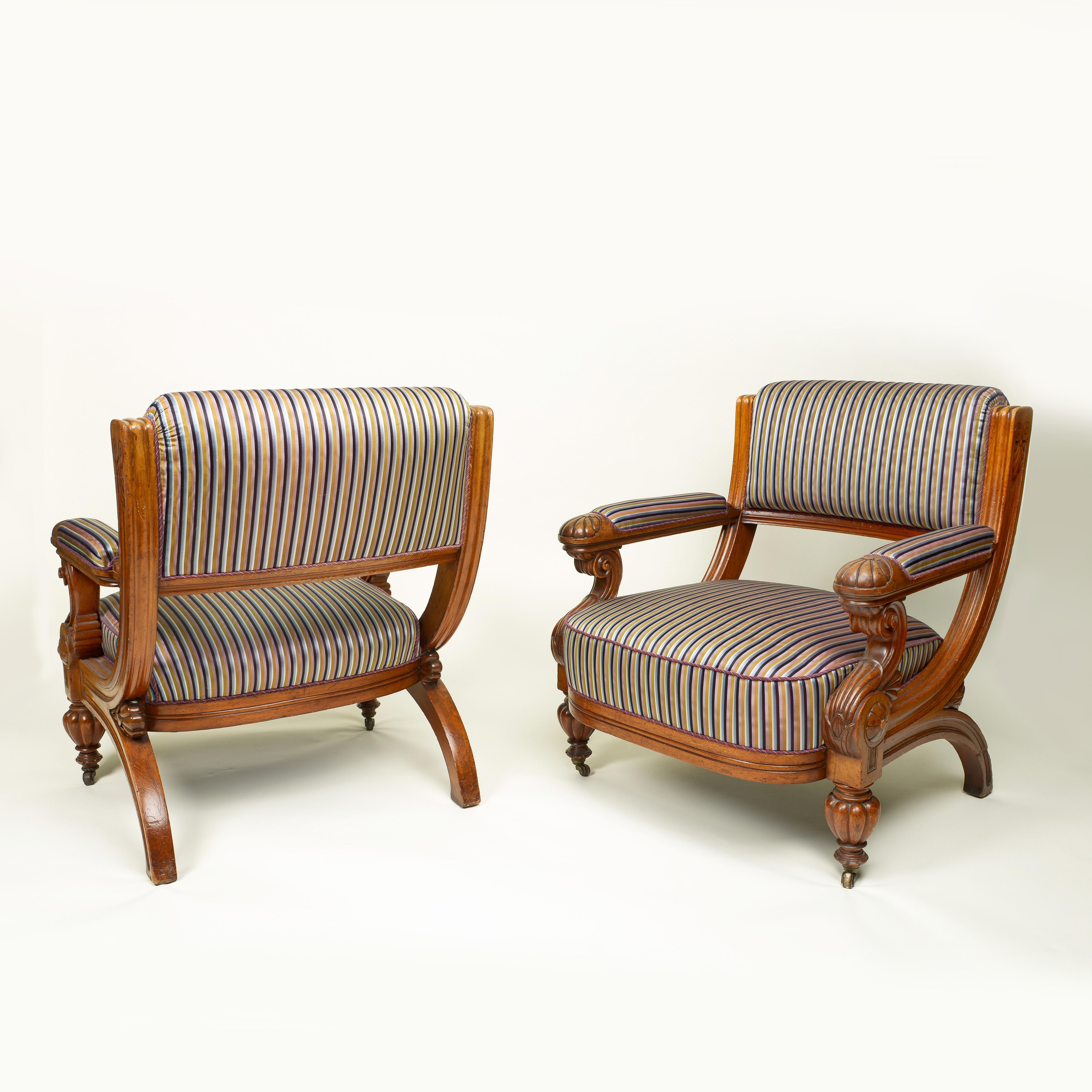 Chacun d'eux présente un dossier et des accoudoirs rembourrés à l'intérieur d'un cadre cannelé, enrichi de motifs floraux et de feuillages stylisés ; l'assise surélevée repose sur une barre d'assise profonde et des pieds avant audacieusement