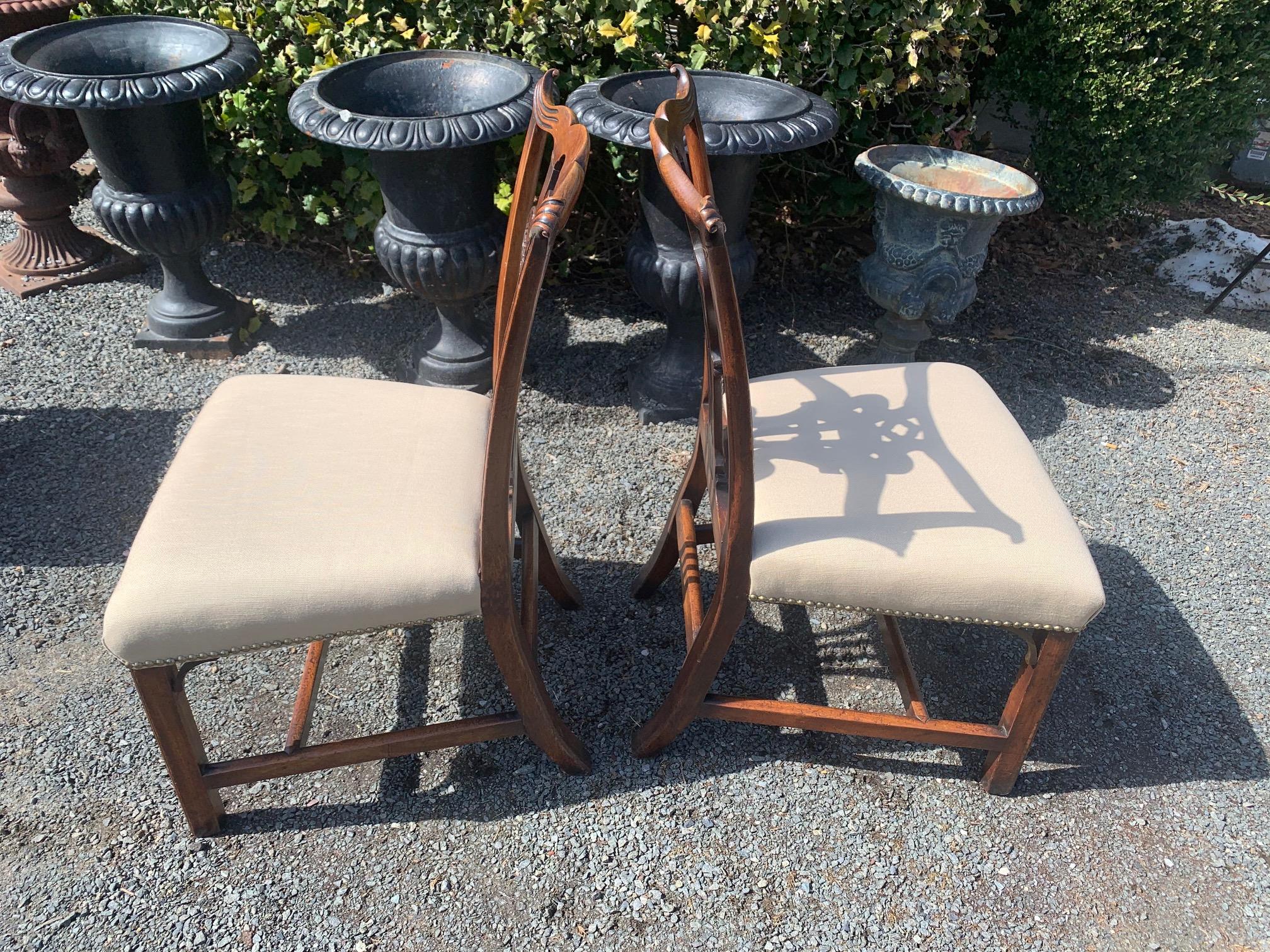 A rare and fine pair of 19th century Chippendale style carved mahogany side chairs having wonderful central tassel and upholstered saddle seats.