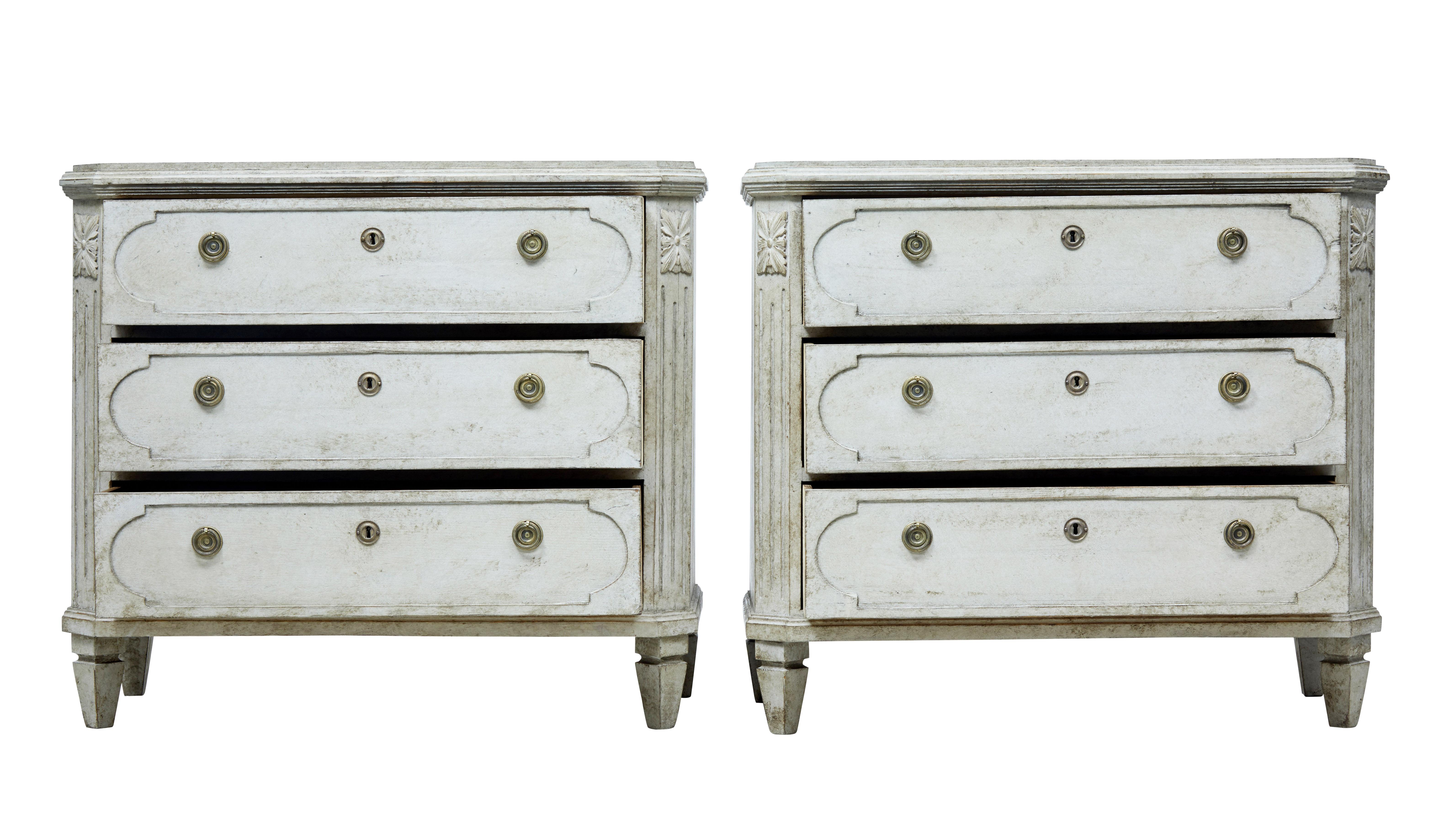 Pair of Gustavian inspired chest of drawers circa 1870.

3 drawer chests with shaped fronts, later ring handles and escutcheons. Canted corners with applied acanthus detailing.

Working locks and key. Standing on short tapered feet.

Later