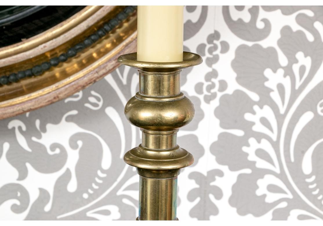 Une belle paire de chandeliers anciens en laiton du 19ème siècle, montés comme lampes de table électriques. Tous deux reposent sur des bases carrées avec des coins cannelés et des chandeliers tournés. Montées avec des douilles pour bougies et