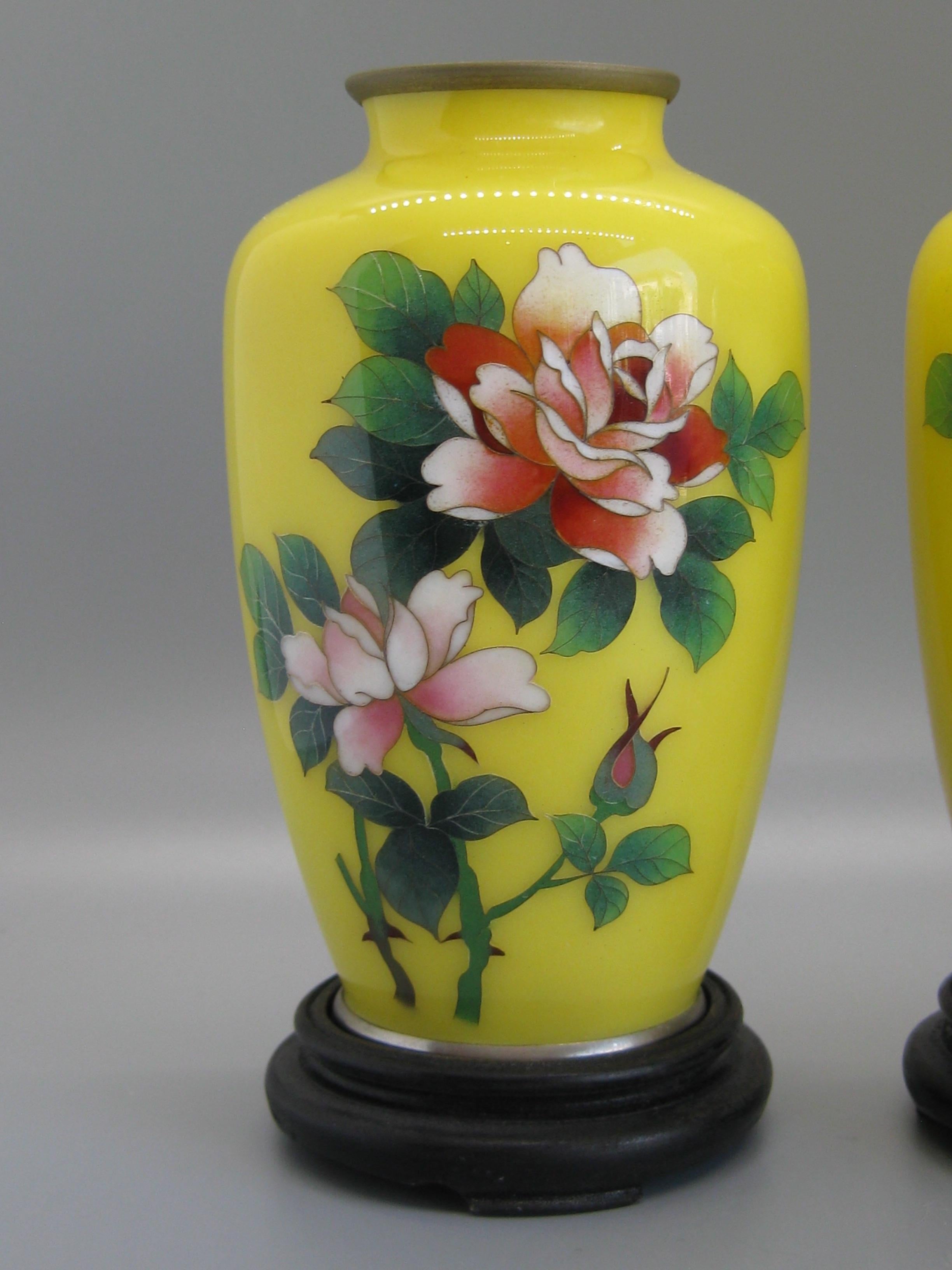 Paire de vases anciens en émail cloisonné japonais datant du début des années 1900. Les deux sont marqués par l'artiste sur le fond. Elles sont attribuées au maître artiste Ando Jubei. Belles roses colorées sur fond jaune. Ils sont livrés avec leurs