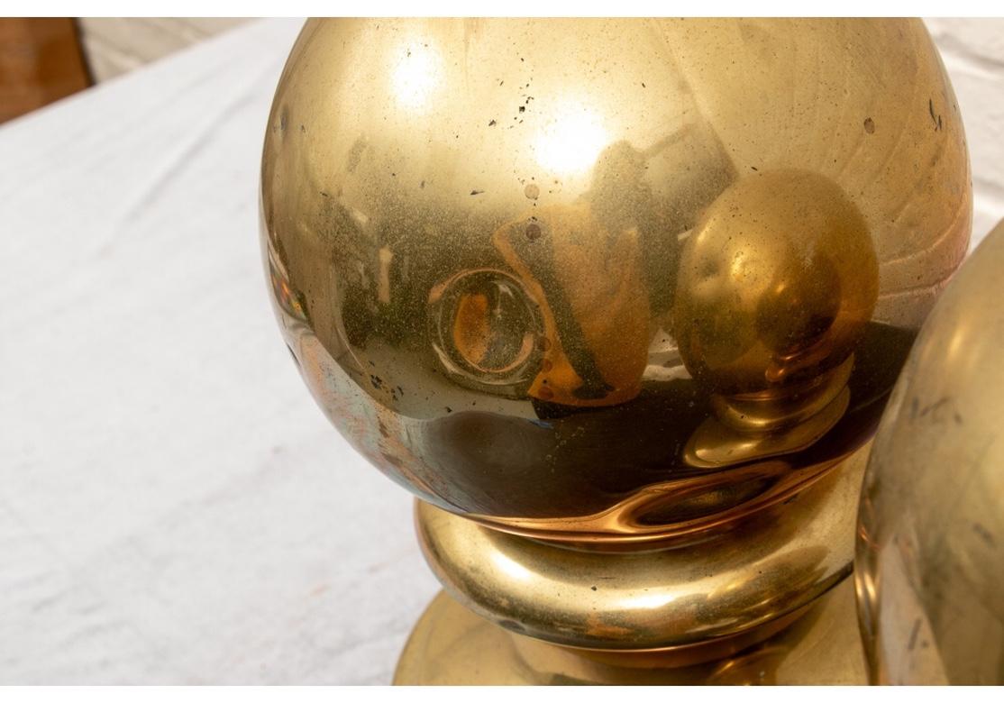 Pair of antique brass bollards. A spherical top over a short turned standard and raised on a circular stepped base. Drill holes along base allowing to be affixed to boat deck. Solid feeling with good weight. Good condition with expected signs of
