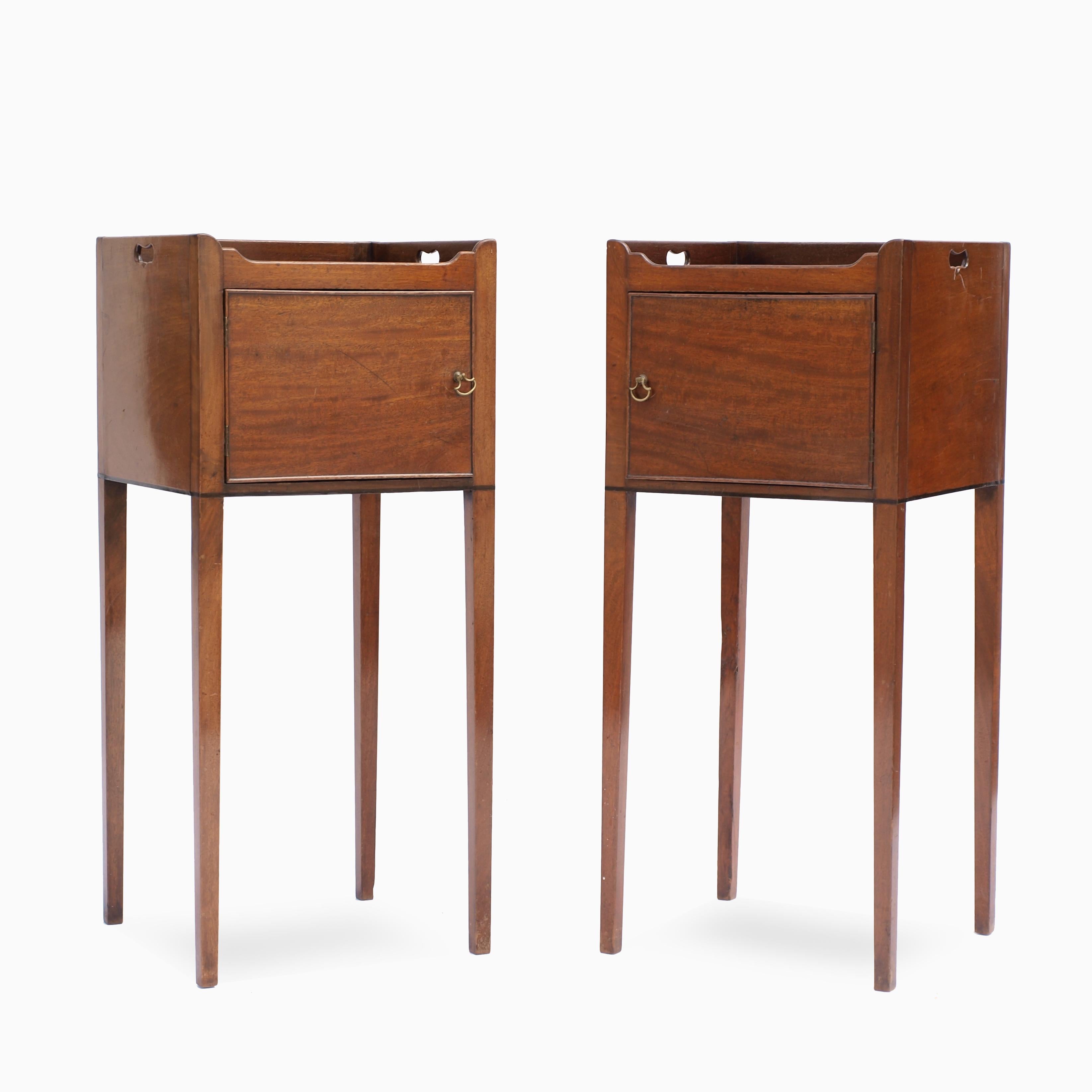 A fine pair of Chippendale period mahogany bedside cabinets, circa 1785, the galleried tops have pierced carrying handles and at the base a single line of ebony inlay, resting on beautifully tapered square legs. The doors of figured mahogany are
