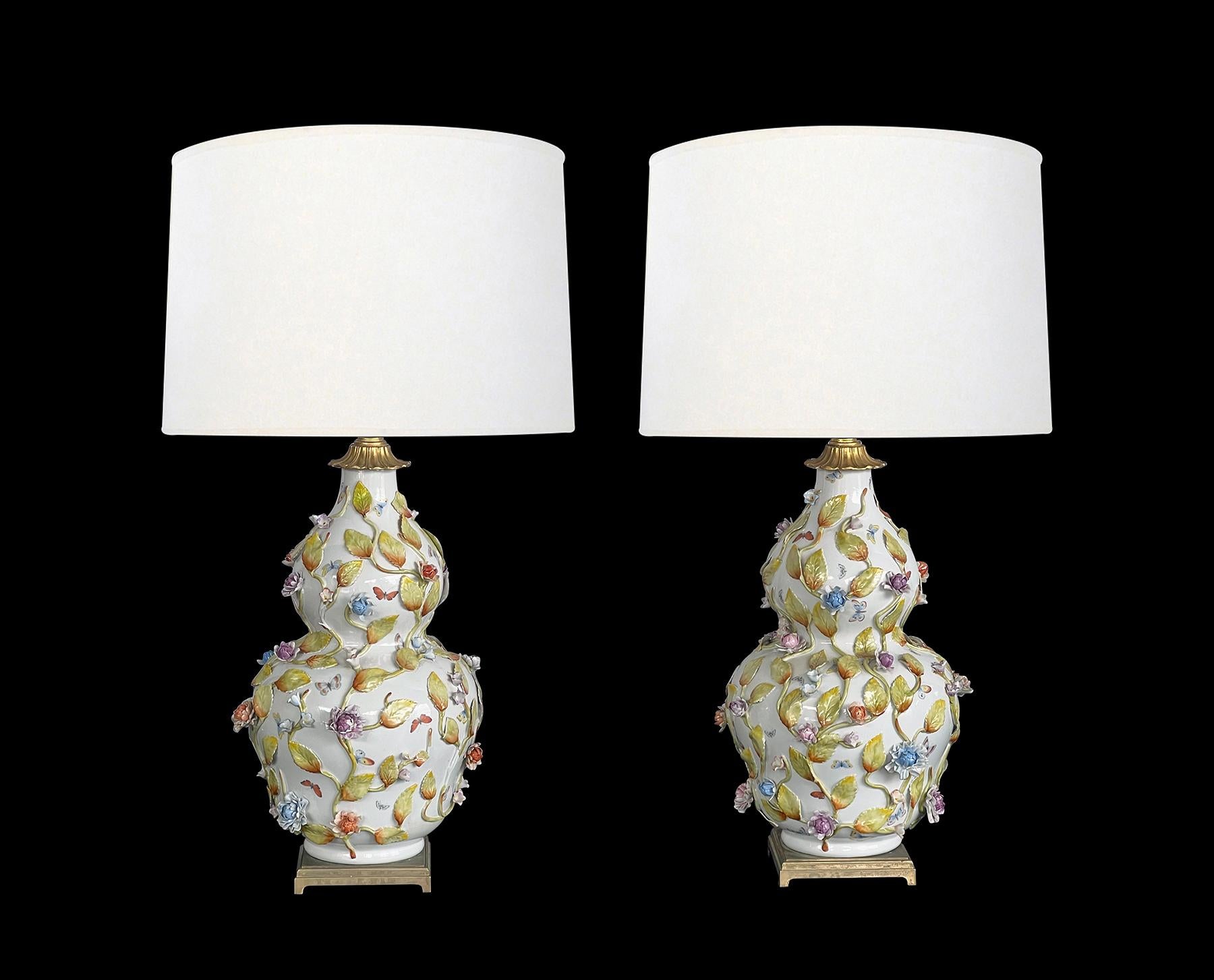 de qualité exceptionnelle, chaque lampe en forme de double gourde avec des papillons peints à la main et des vignes florales et feuillues polychromes en relief, le tout sur un fond émaillé blanc ; hauteur : 18