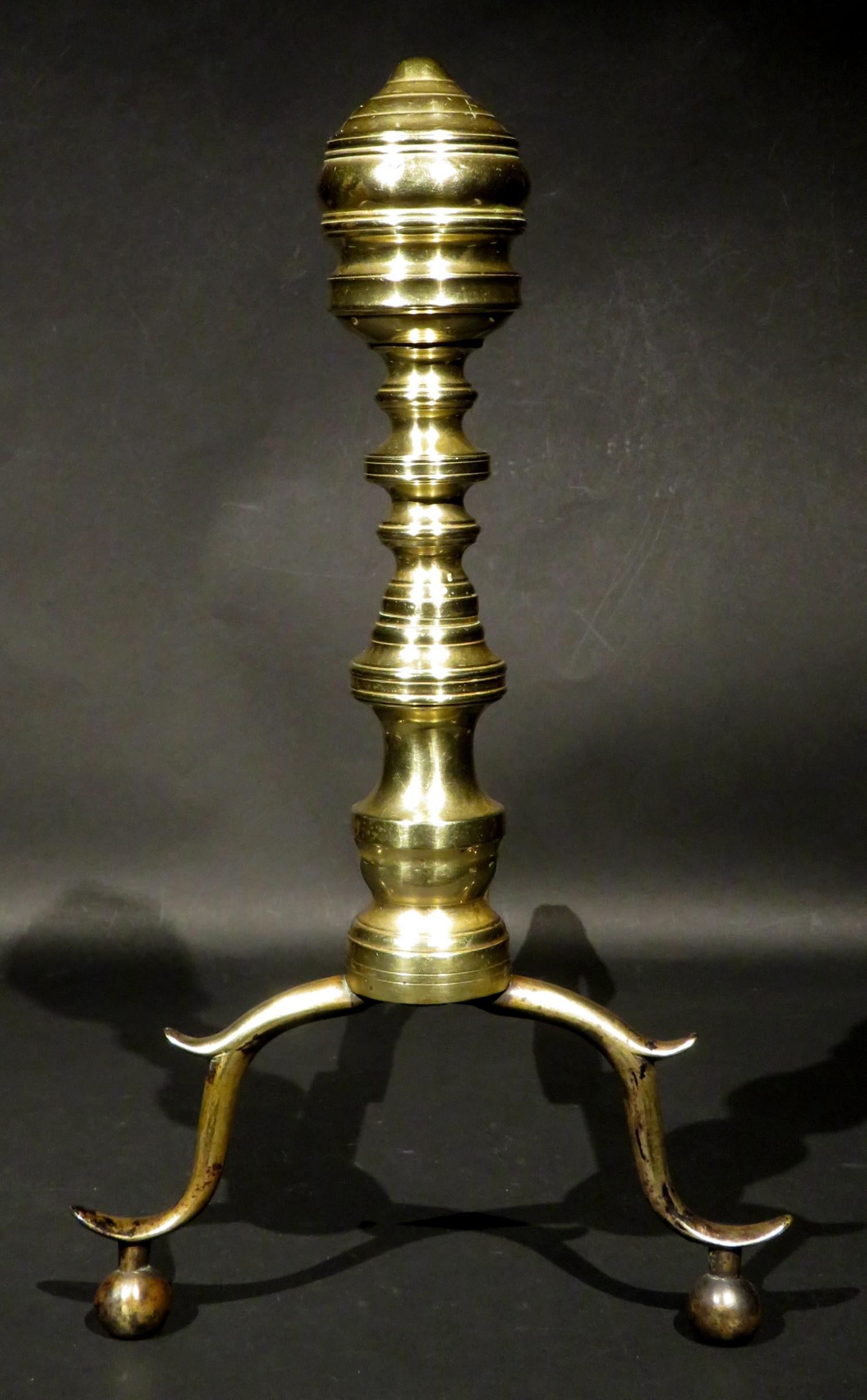 A handsome pair of American Federal Period beehive brass andirons, both showing turned and compressed capitals on sectional columns rising from double spurred and hipped supports, both affixed to their original forged iron 'dogs', with one showing a