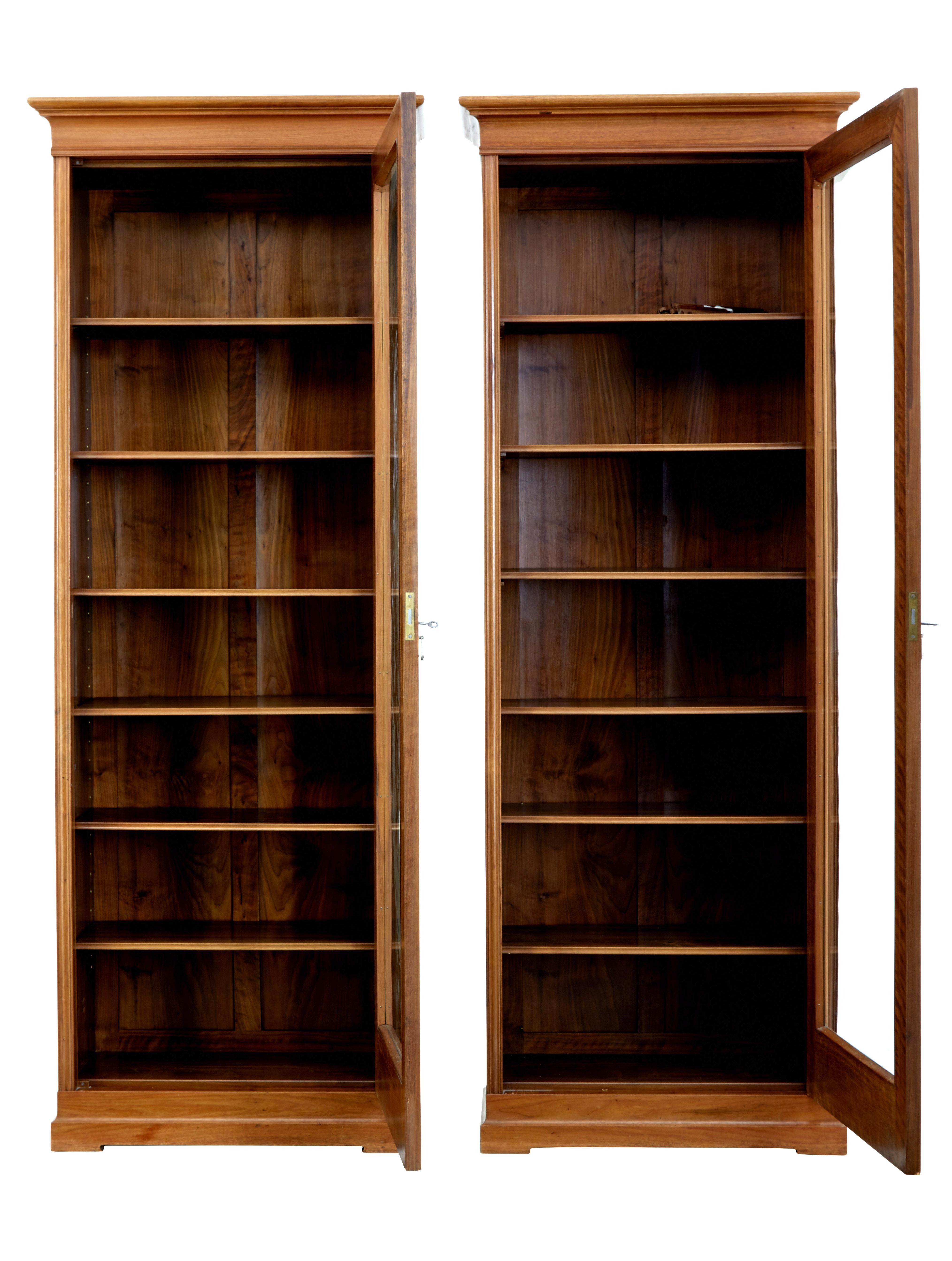 Pair of handmade walnut tall bookcase's, circa 1900.

Shaped cornice to the top. Each with a single glazed door which opens up to 6 adjustable shelves, standing on a plinth shaped base.

Elegant pieces, which due to their handmade natural the