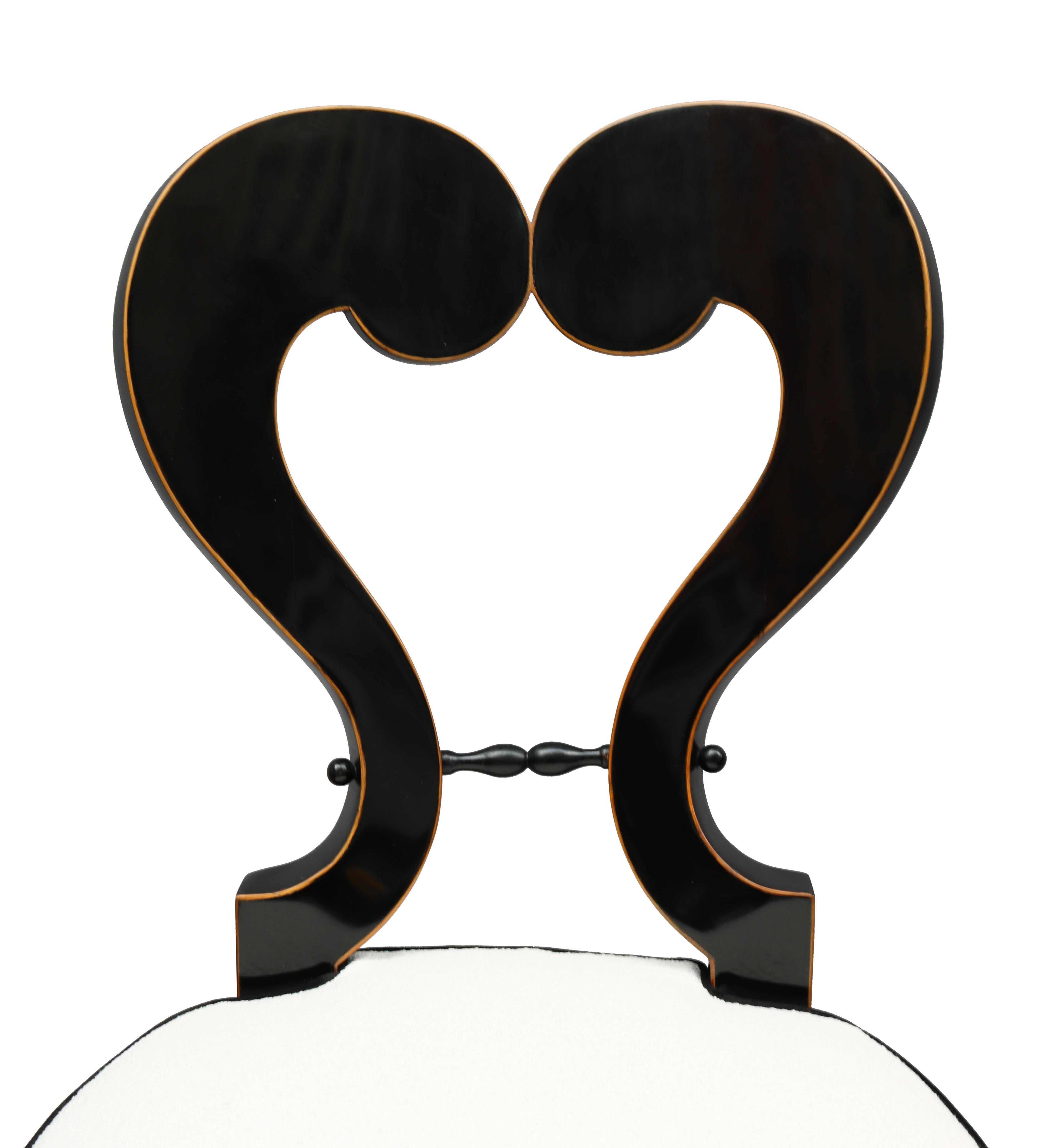 Pair of important Biedermeier side chairs in the manner of Josef Danhauser. Crafted from ebonized fruitwood with border of intricate pearwood inlay. Resting on four tapered sabre shaped legs and backrest with stylized heart shaped cut out detail.