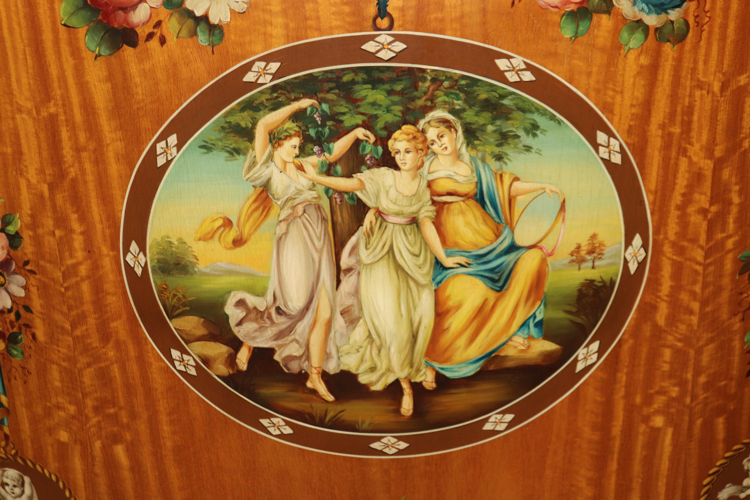This is a spectacular pair of hand-painted satinwood commodes. They were made during the 1920s era. The commodes feature exceptional paint decorated nymphs and floral scenery. The commodes are in good condition with no real issues to speak of but