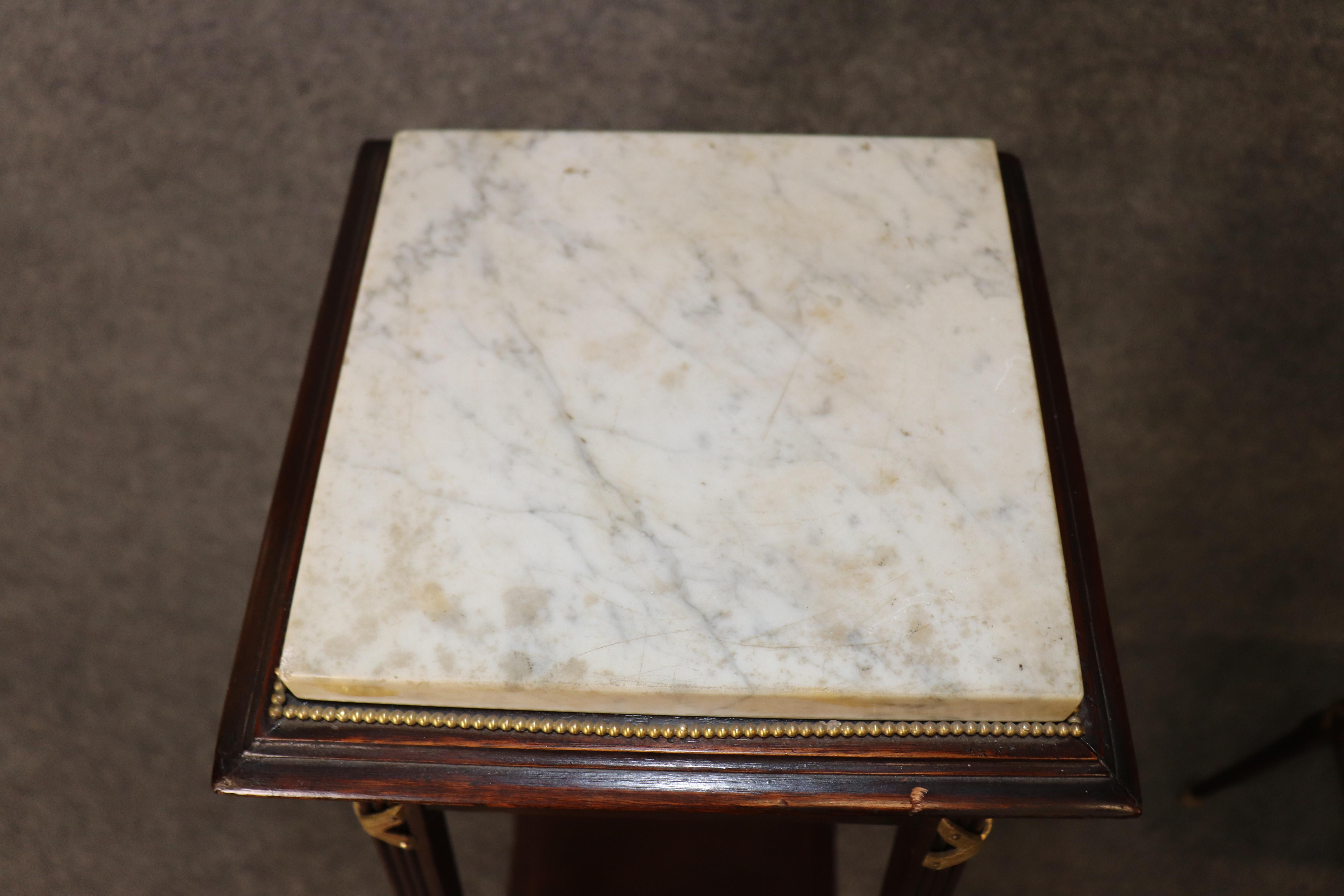 Elevate your interior with this elegant pair of 1930s era walnut pedestals or plant stands, featuring beautifully grained wood and luxurious marble tops. These antique stands are ideal for displaying plants, sculptures, or decorative objects,