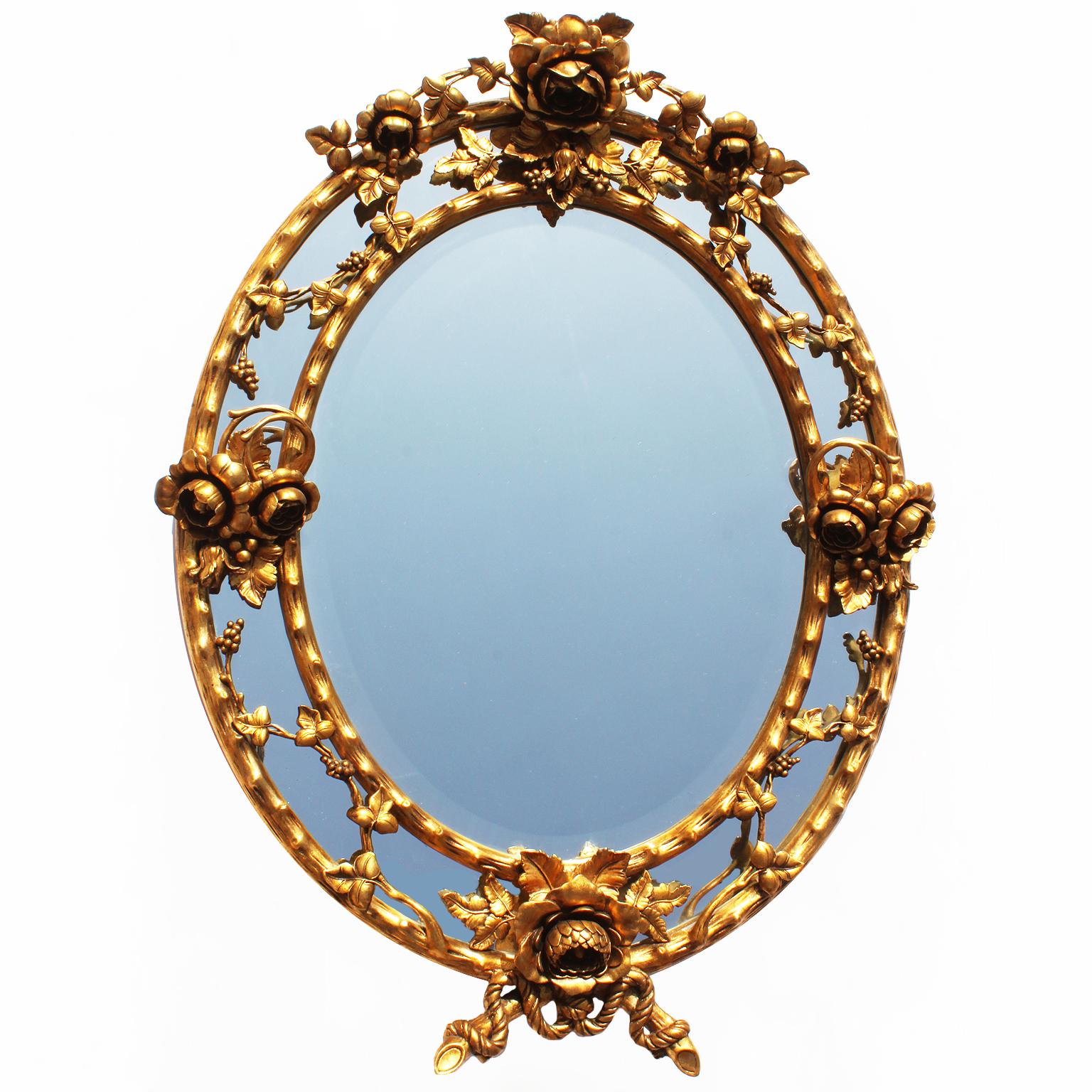 A fine pair of French Belle Époque giltwood and gesso carved oval mirror frames. The ornately carved frames, each topped with a flower bouquet among leaves and grape vines, the body of the frame resembling a tree branch, flanked on each side with a