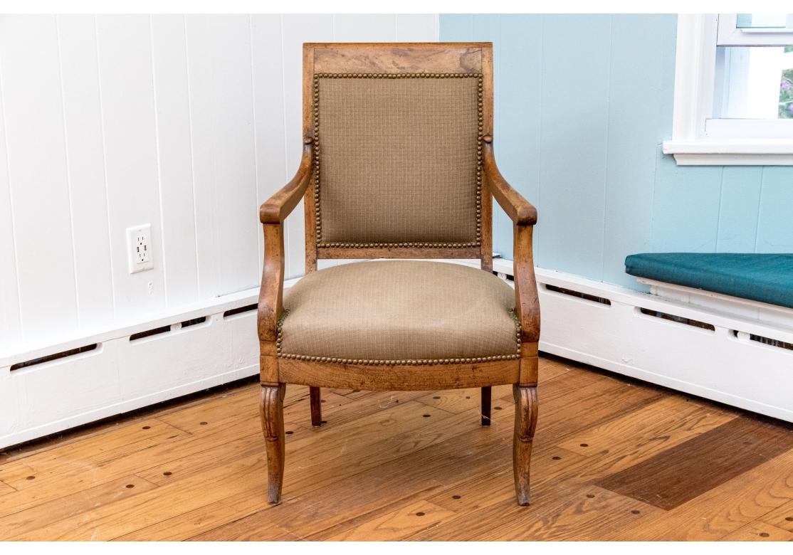 Pair of burl walnut Empire style armchairs with upholstered seats and backs featuring fine craftsmanship with a square top rail and stylized carved accent on front of each arm support and a carved detail at the top of cabriole legs. The chairs are