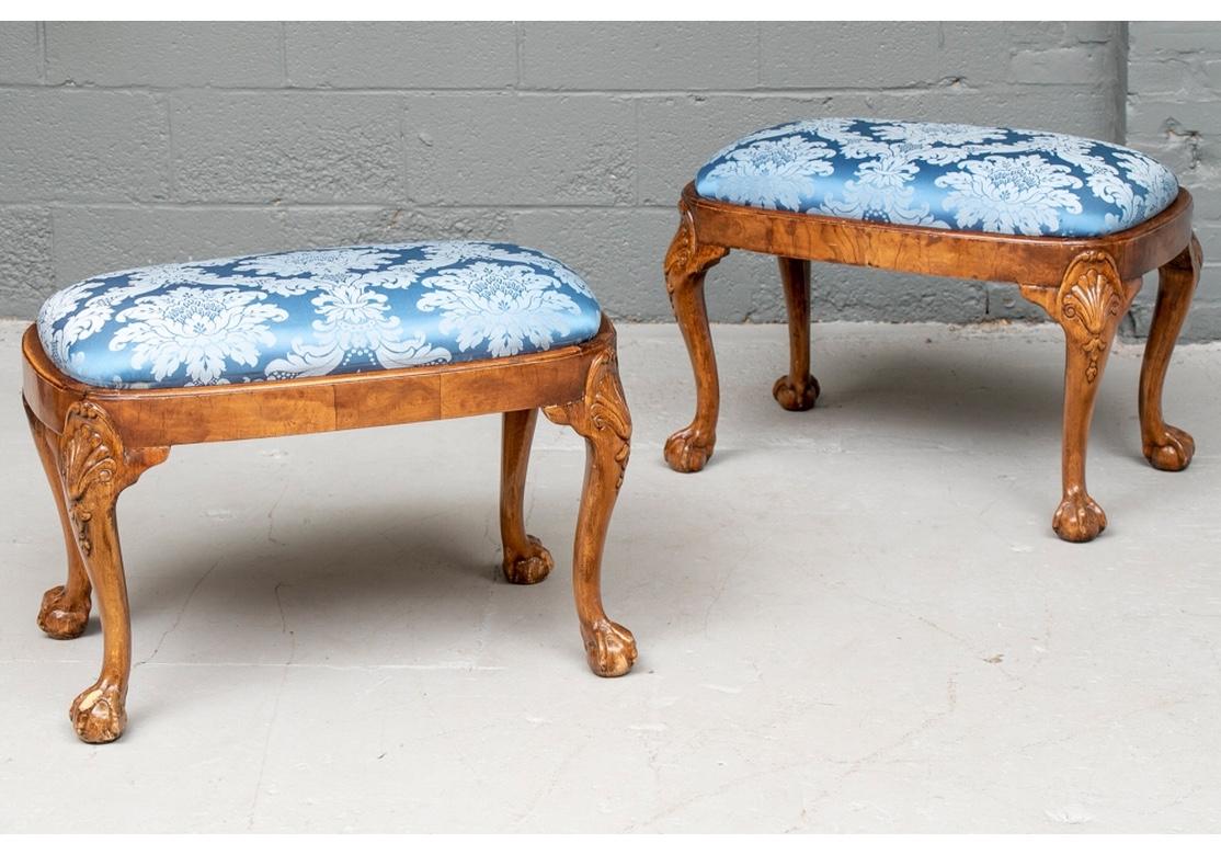 The pair in a handsome deep amber tone walnut with good graining. Rounded rectangular benches raised on carved cabriole legs with shell knees and ball-and-claw feet. The slip seats newly upholstered in a fine blue satiny damask fabric.
Measures: