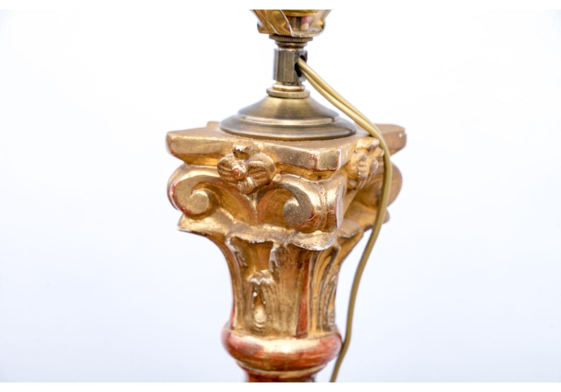 Pair of Italian-style giltwood table lamps, featuring a distinctive Solomonian or barley twist column design surmounted on ebonized plinth bases. The top of the lamp with a Corinthian capital and the base with a square paneled motif. The lamp with