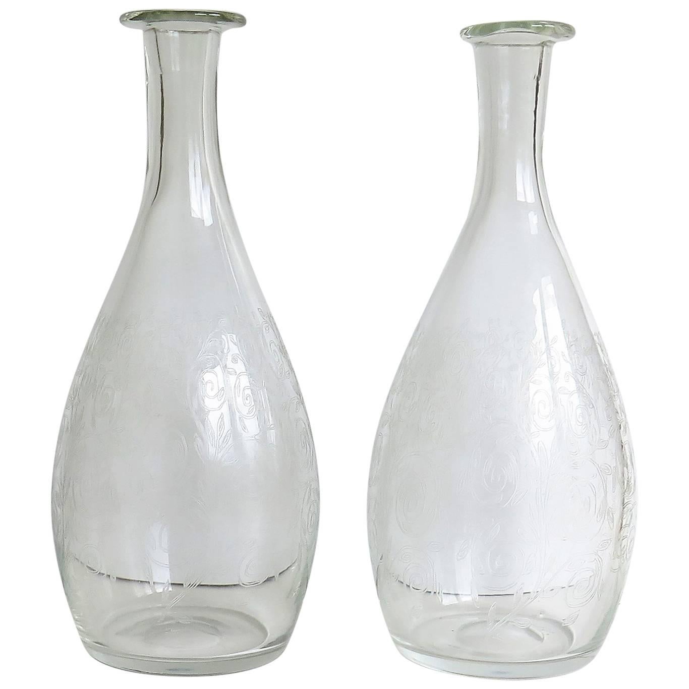 These are a fine pair of hand blown, English, lead crystal glass carafes, decanters or bottle vases dating to the 19th century.

The carafes are bottle shaped, tapering to the neck with nicely lipped rims. They have ground out pontil marks to the