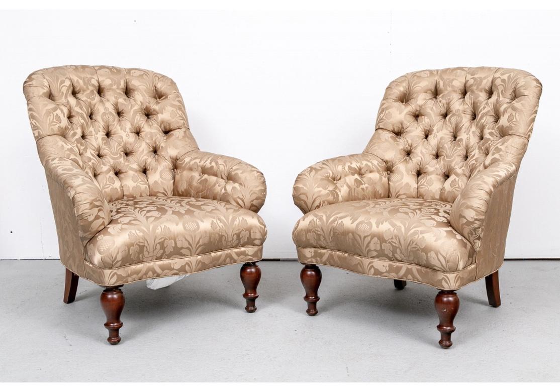A fine pair of fireside club chairs in an olive green silky damask style upholstery. The backs and arms with rolled edges and button-tufted backs and inside the arms. With a shaped seat in front, and raised on turned front legs and square splayed