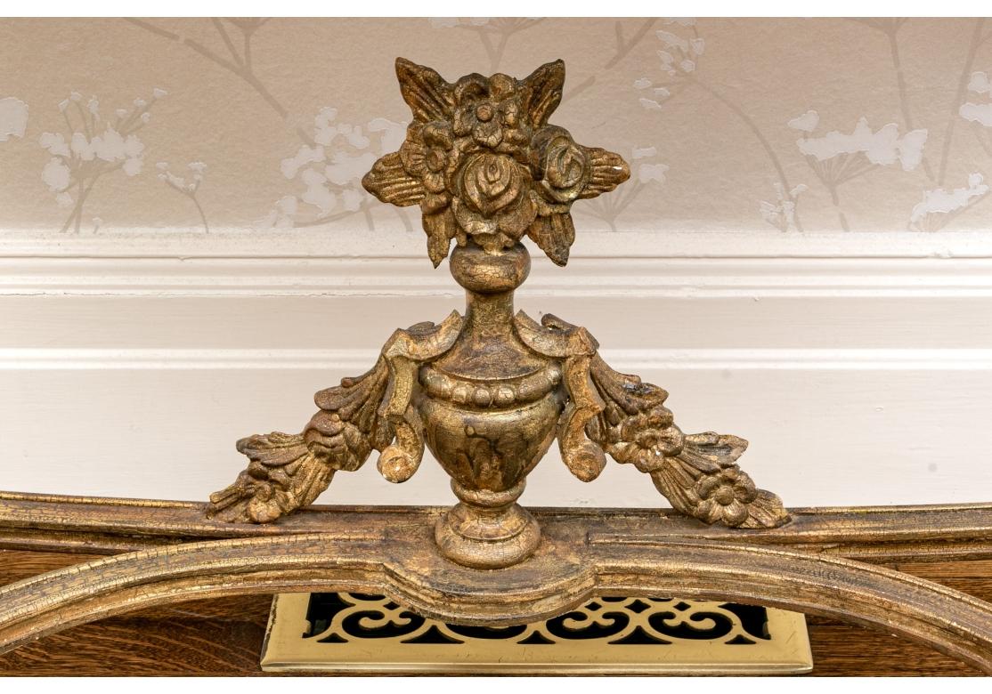 An exceptional pair of gilt wood Console Tables with extensive foliate carved frames including Swags, Flowers and Leaves with tapered and fluted legs. The bowed stretcher surmounted by an Urn with flowing foliage. The refined finish is in an