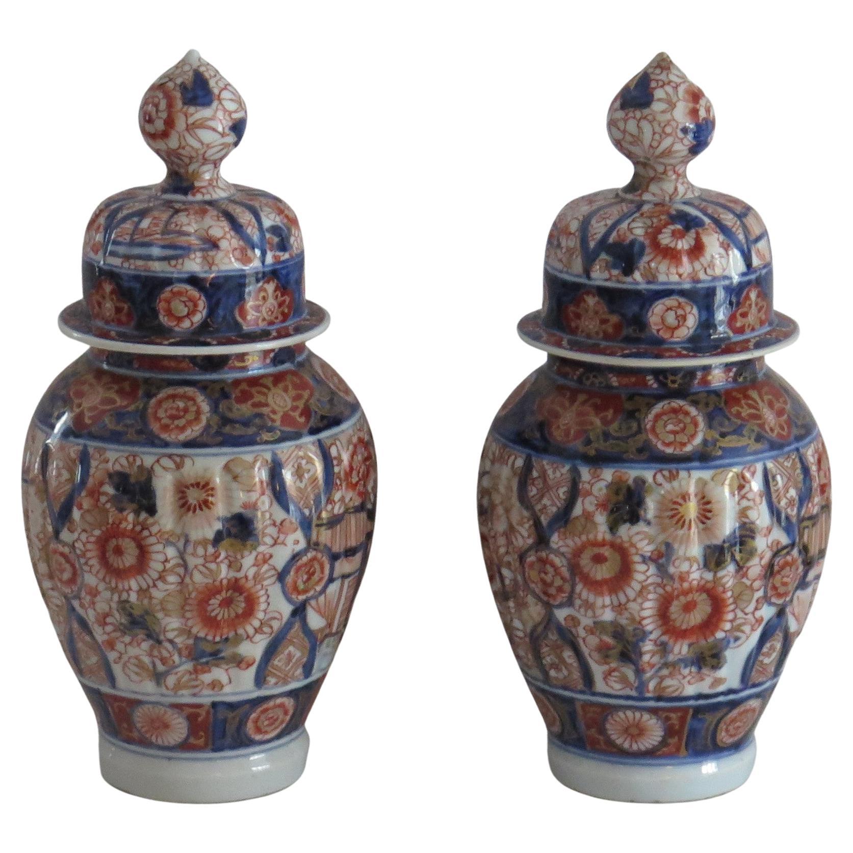 These are a high quality pair of very decorative gilded hand enameled Japanese porcelain lidded vases which we date to the Edo period of the 19th century, circa 1830.

Each vase has a baluster open necked shape and has been hand painted in an Imari
