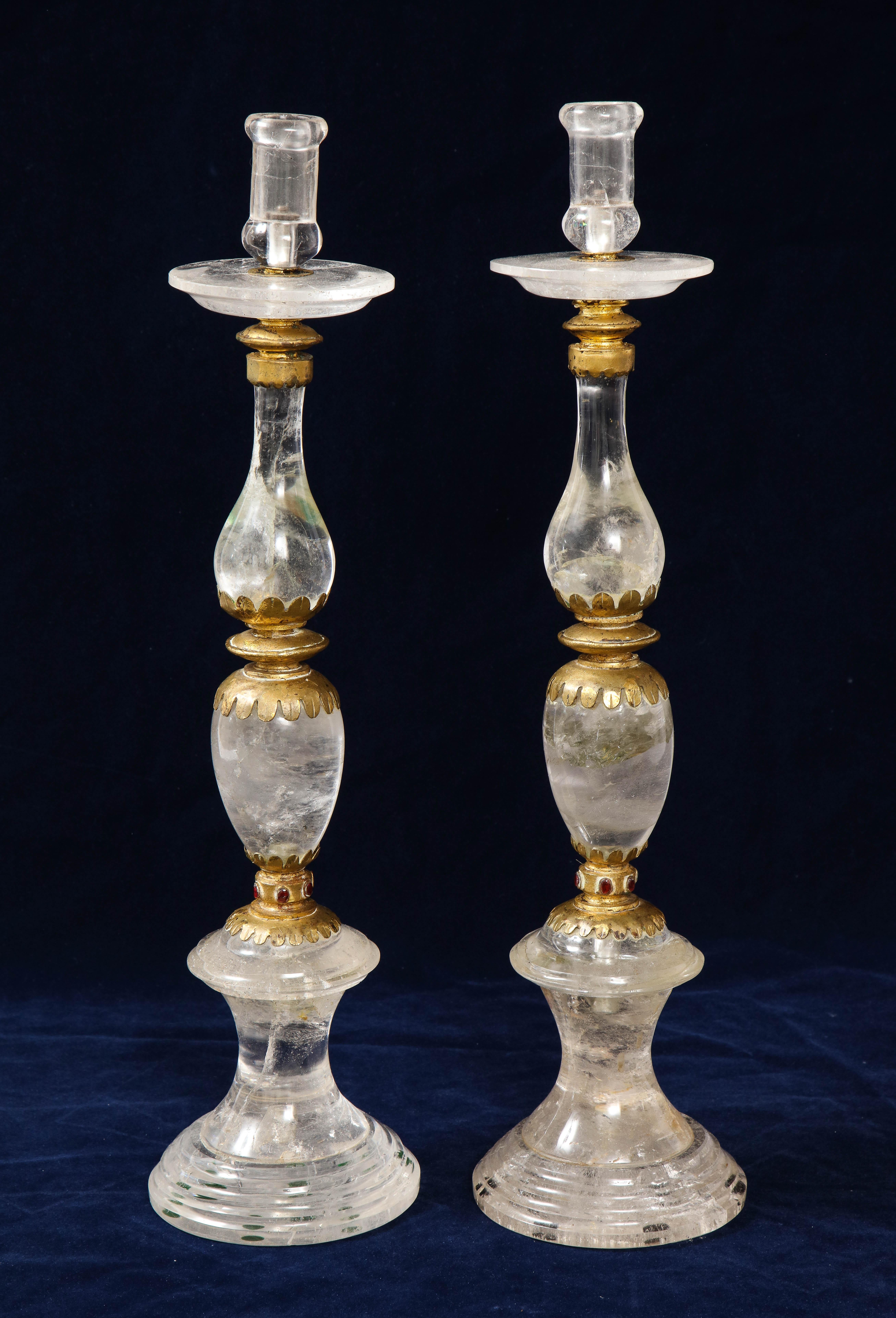 A fine and very large pair of jeweled French Art Deco rock crystal candlesticks, with mercury gilded bronze mounts. The multi shaped elements are adorned by 3 carat hand faceted ruby red garnets on each side and blend into a harmonious whole. These