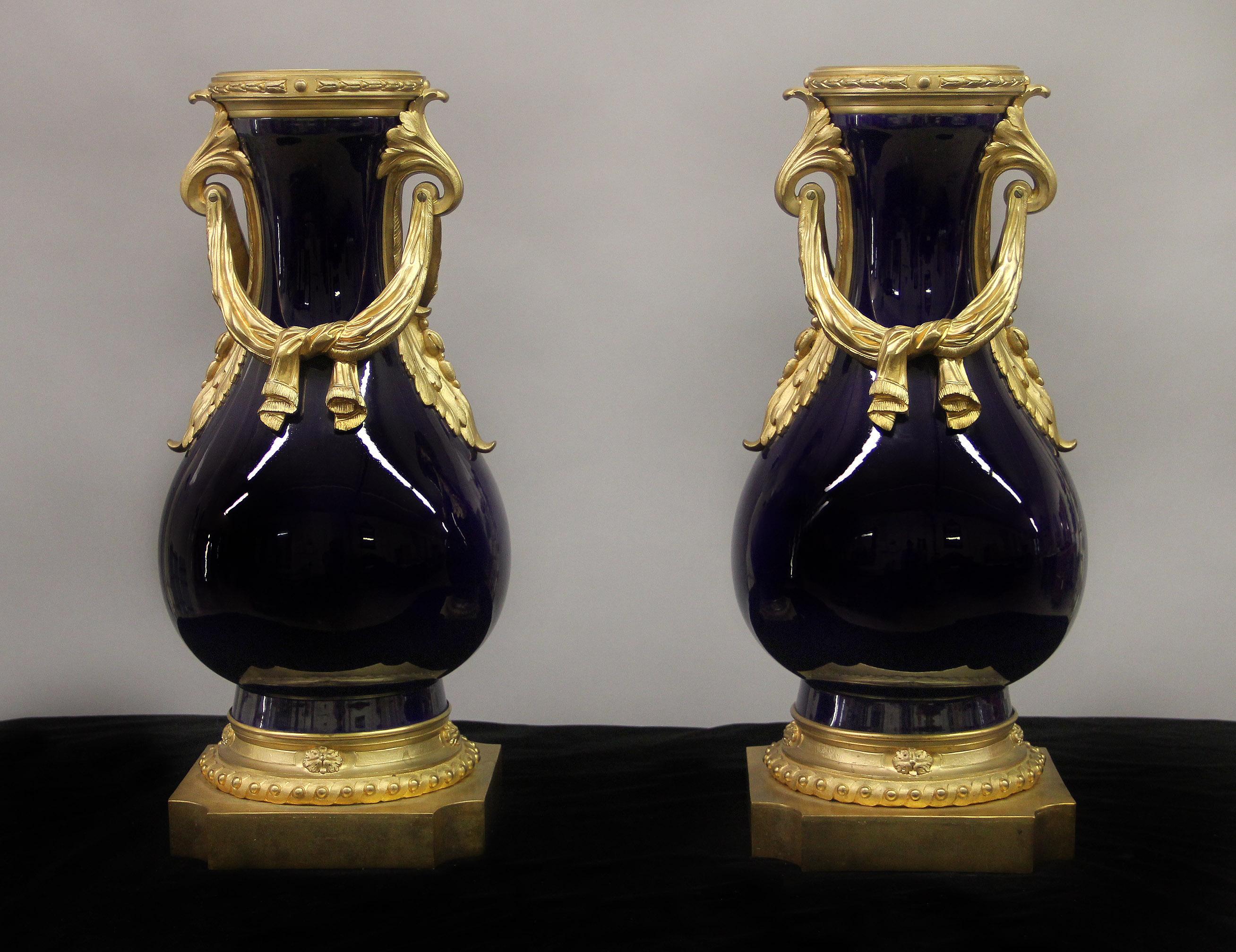 A fine pair of late 19th century gilt bronze mounted Sèvres style porcelain vase.

The cobalt blue vases mounted with tied bronze drapes and handles. 

In late 1739-early 1740 the Sèvres Porcelain Factory opened in the Royal Château of