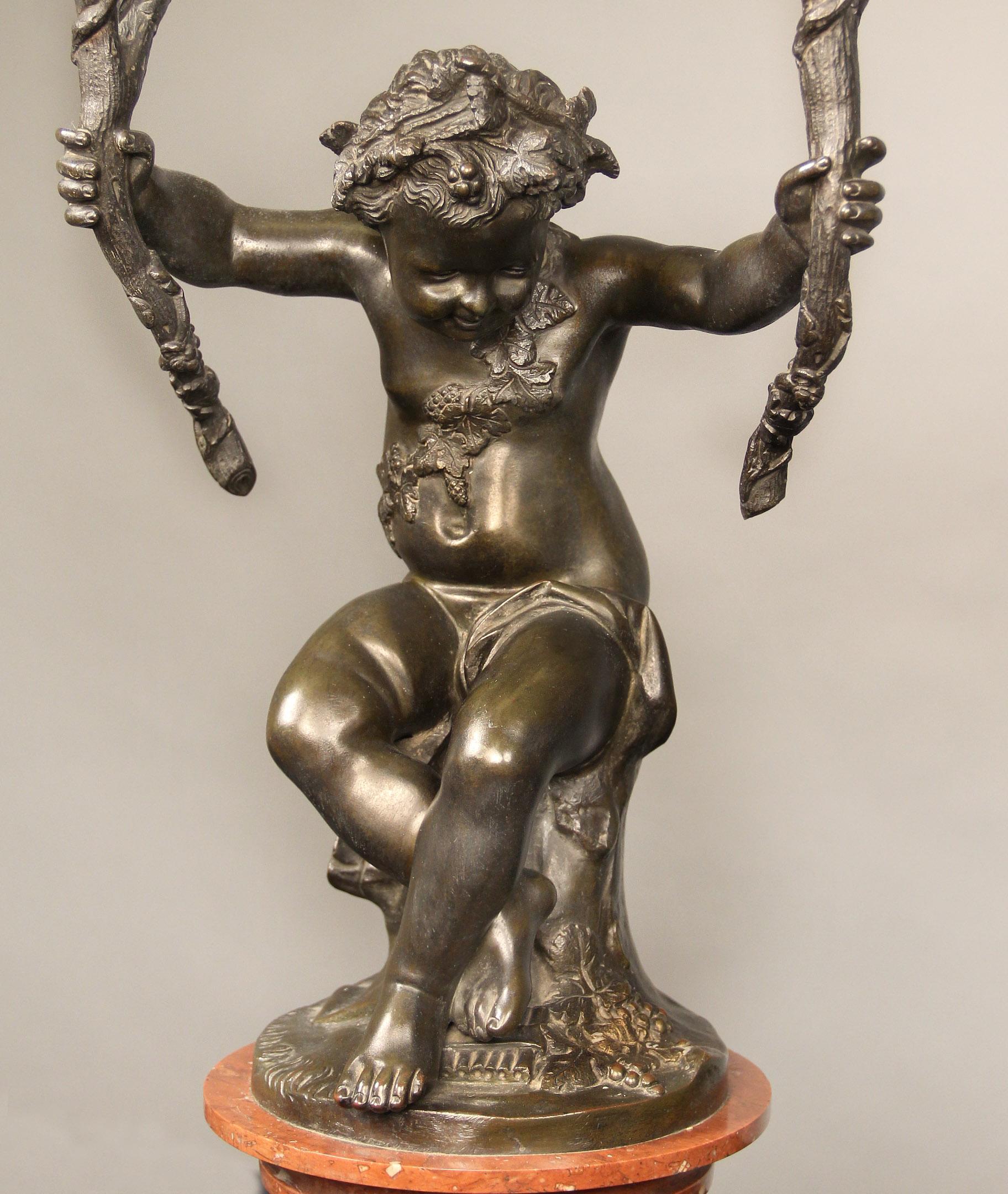An interesting and fine pair of late 19th century patinated bronze and marble four light candelabra

After Claude-Michel Clodion

The large figures modeled as a putti with a branch in each arm, entwined in leaves and berries, leading to two
