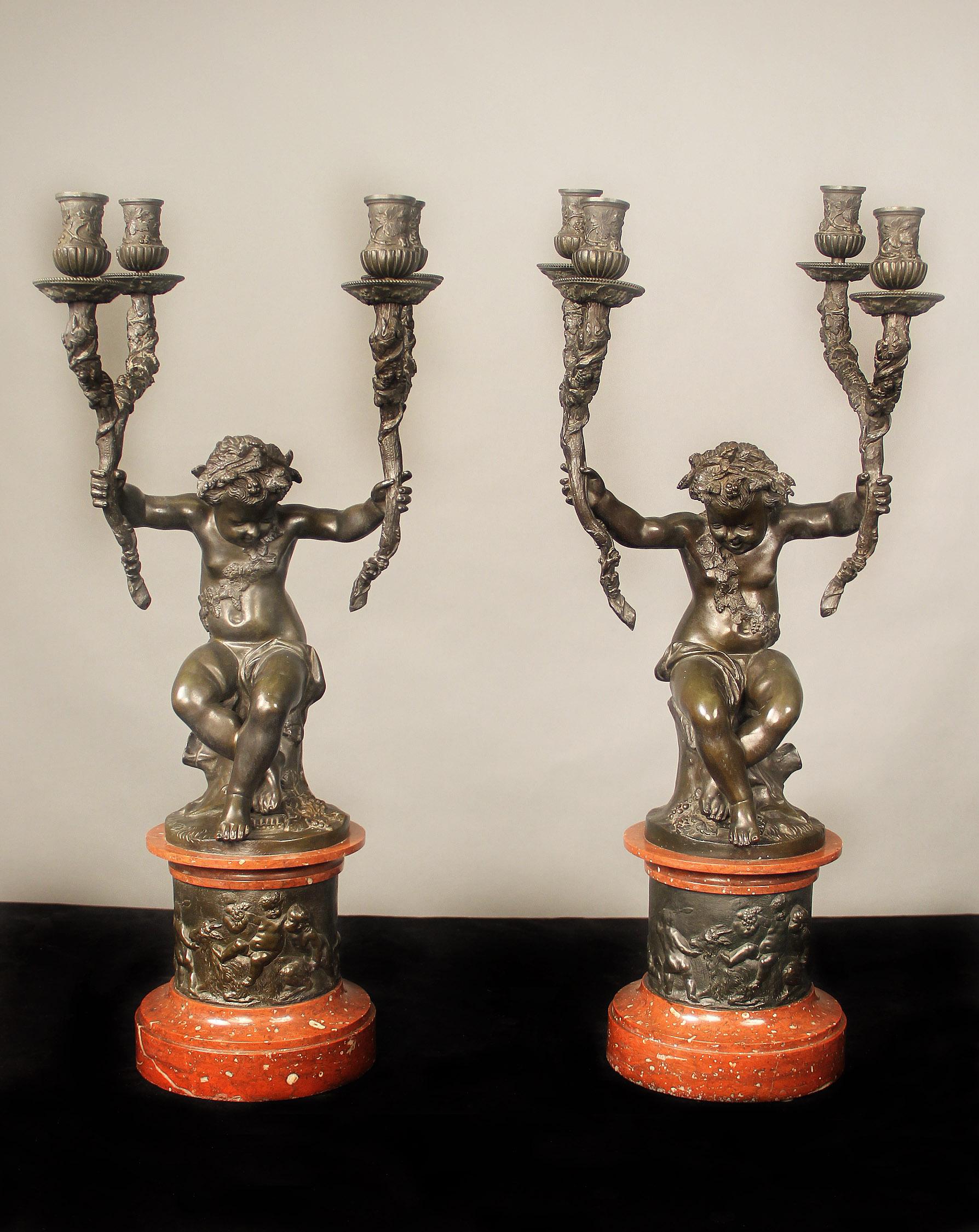 Un'interessante e raffinata coppia di candelabri a quattro luci in bronzo patinato e marmo della fine del XIX secolo

Dopo Claude Michel Clodion

Le grandi figure modellate come putti con un ramo in ciascun braccio, intrecciato con foglie e bacche,